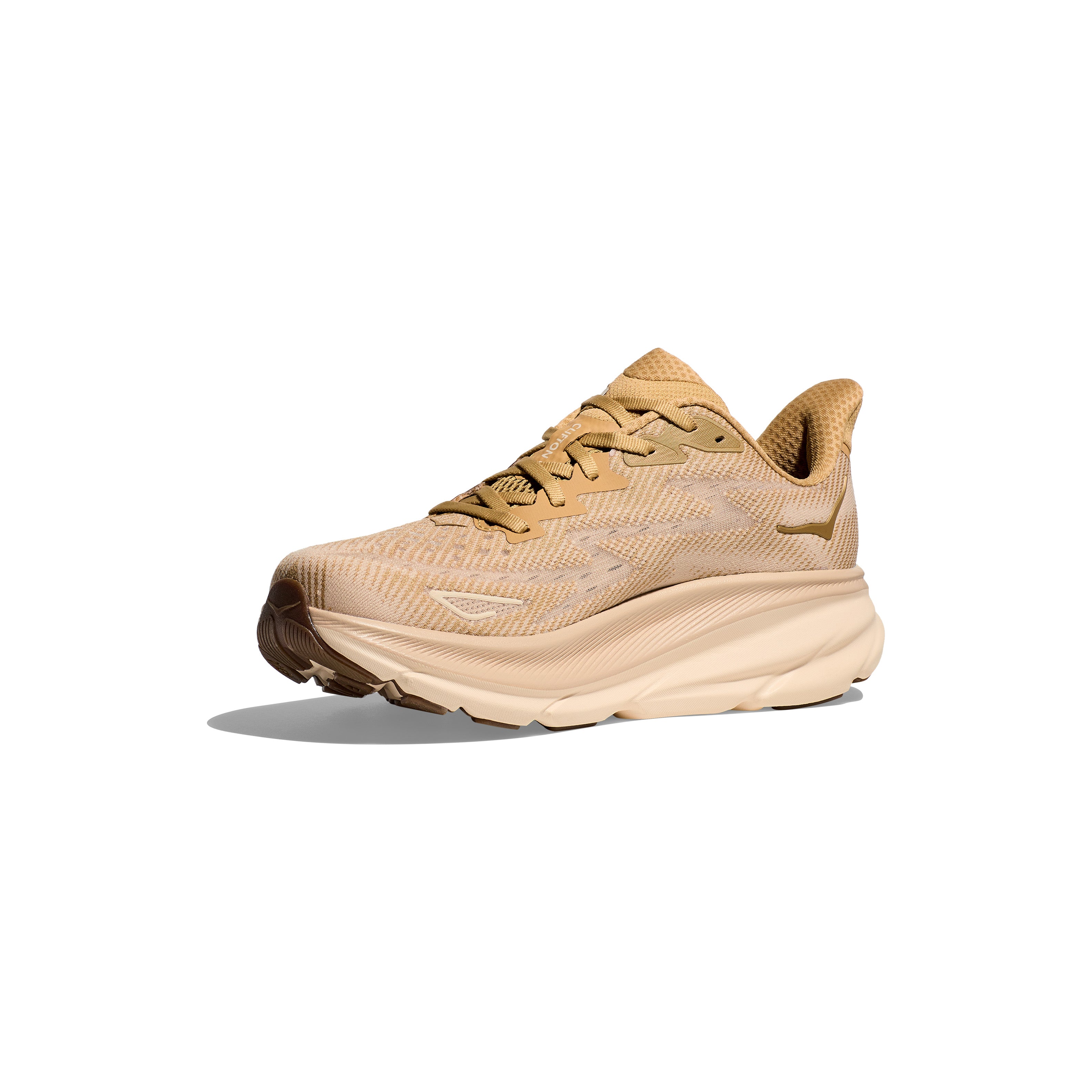 The Hoka M Clifton 9 in Wheat/Shifting Sand features a thick Clifton 9 cushion and mesh upper for responsive toe-off. Beige athletic running shoe displayed on a white background with a slight shadow.