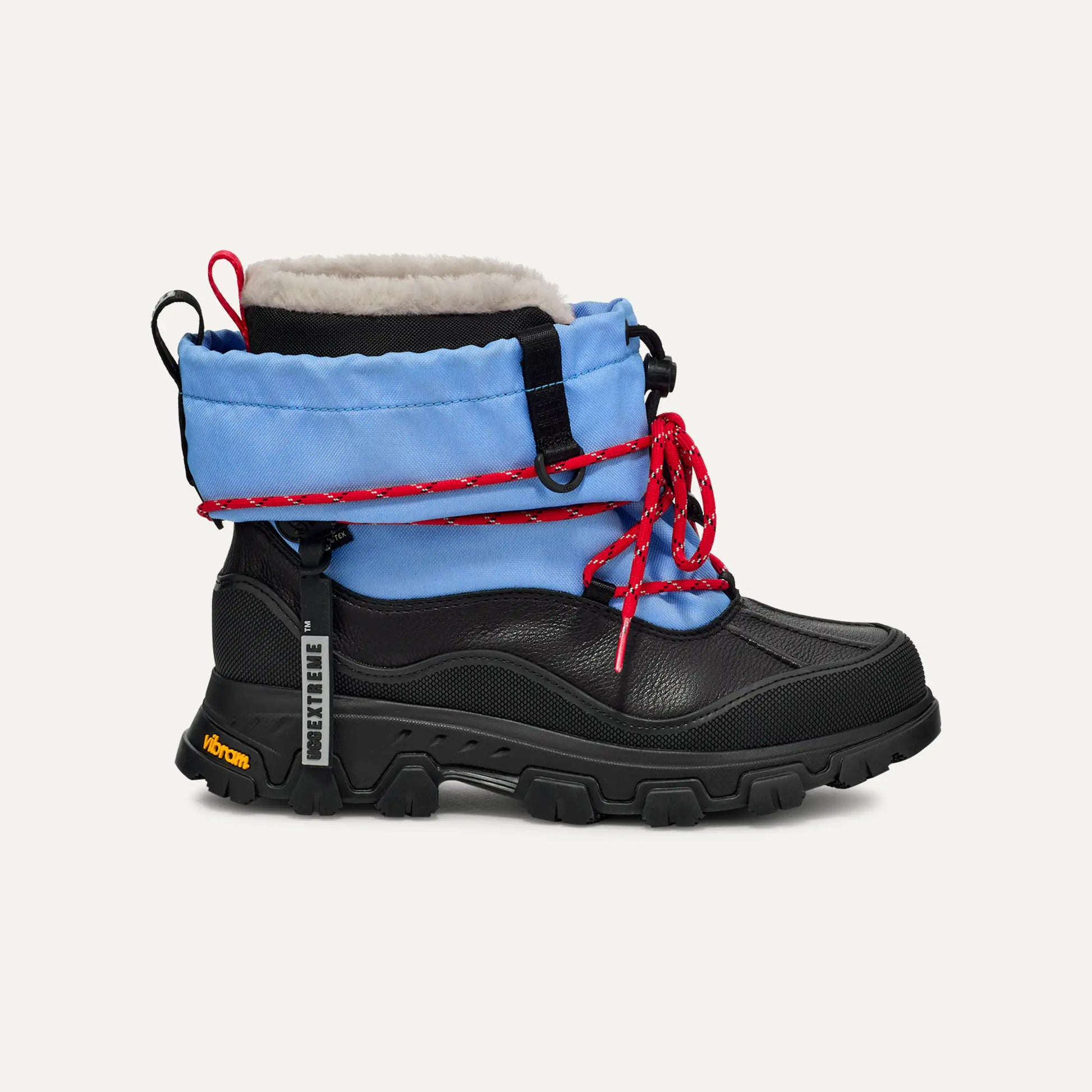Introducing the Ugg W Metropeak: a high-top boot with a black sole and toe, blue upper, red laces, "Extreme" label, and Vibram logo. Waterproof and warmth-focused, it boasts a fur-lined interior.