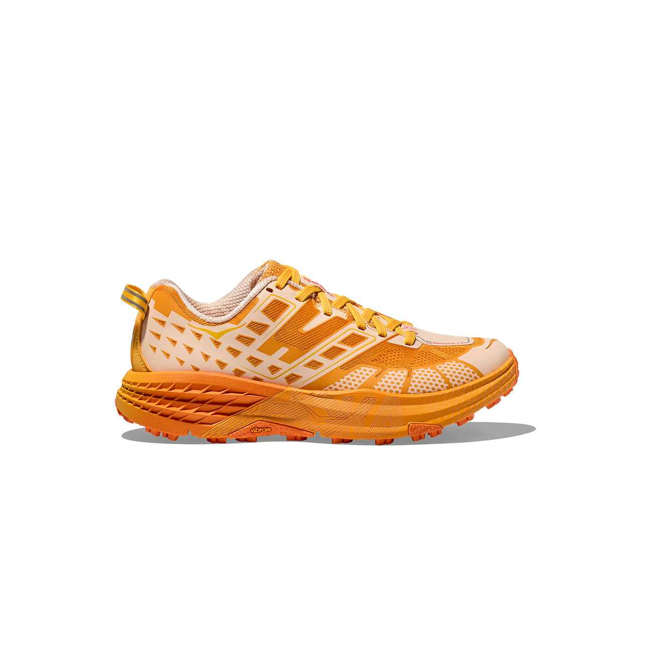 A side view of the Hoka U Speedgoat 2 trail running shoe in orange and yellow, featuring Vibram lugs, a textured sole, and geometric patterns on the upper.