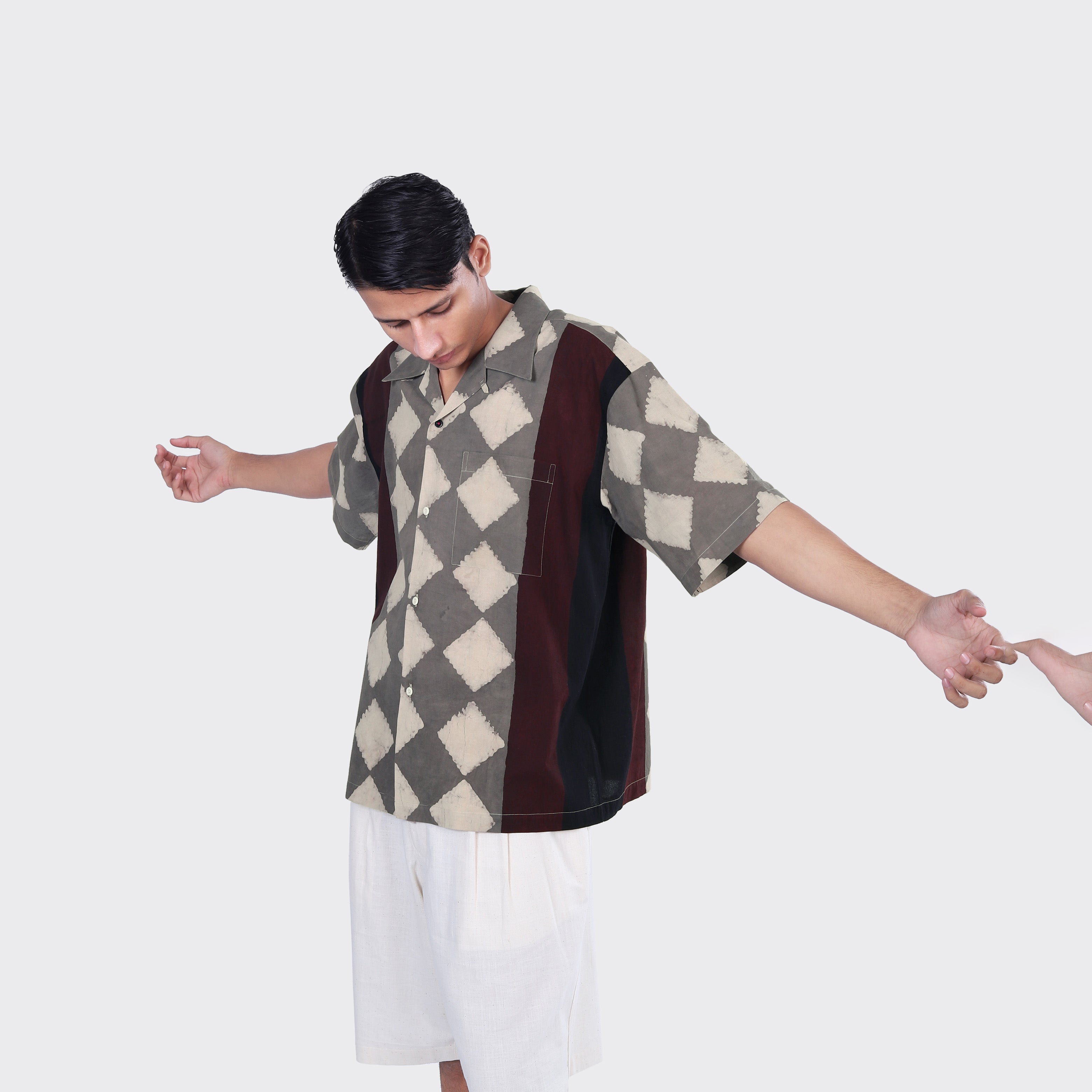 A man wears the Kardo Rohit Shirt, Block Print 139, and white shorts, standing with arms outstretched against a plain background. Another hand is seen holding his right hand.