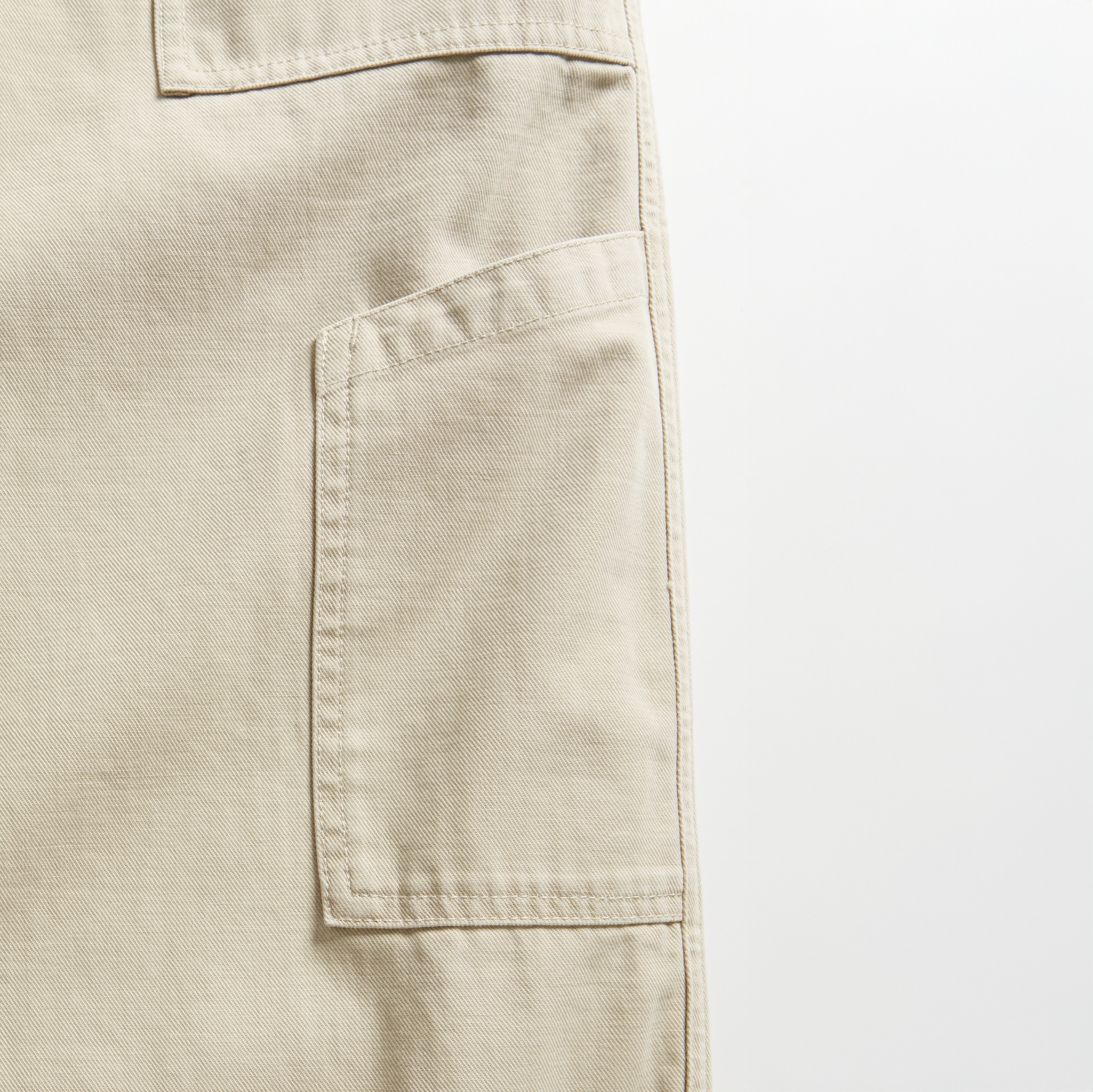 Close-up of a beige D-Series Utility Pant by Dockers, showing a large side pocket with visible stitching, set against a plain white background.