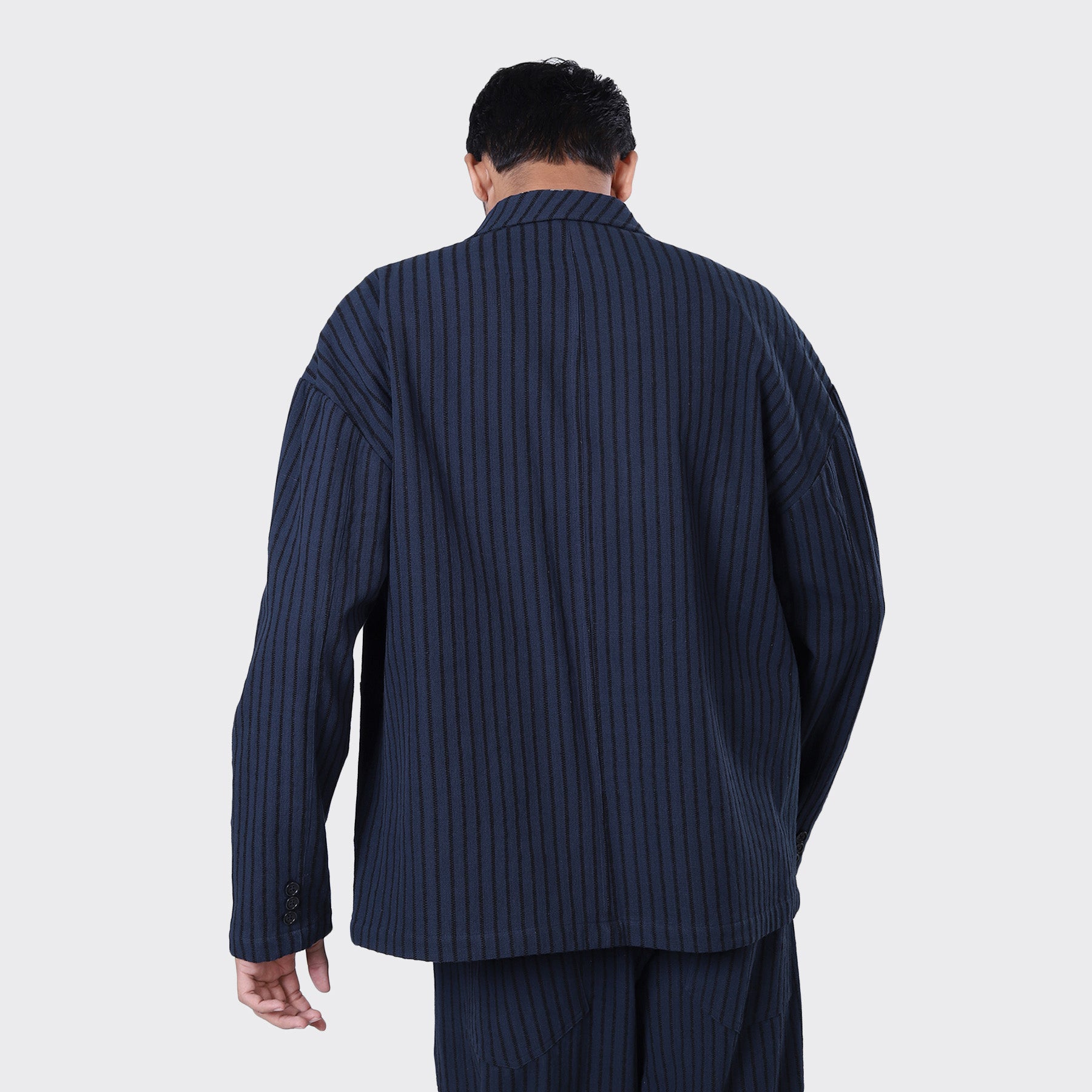 A person facing away, wearing Kardo's Hugh 2.0 Blazer in Blue Black Stripe with matching pants, set against a plain light background.