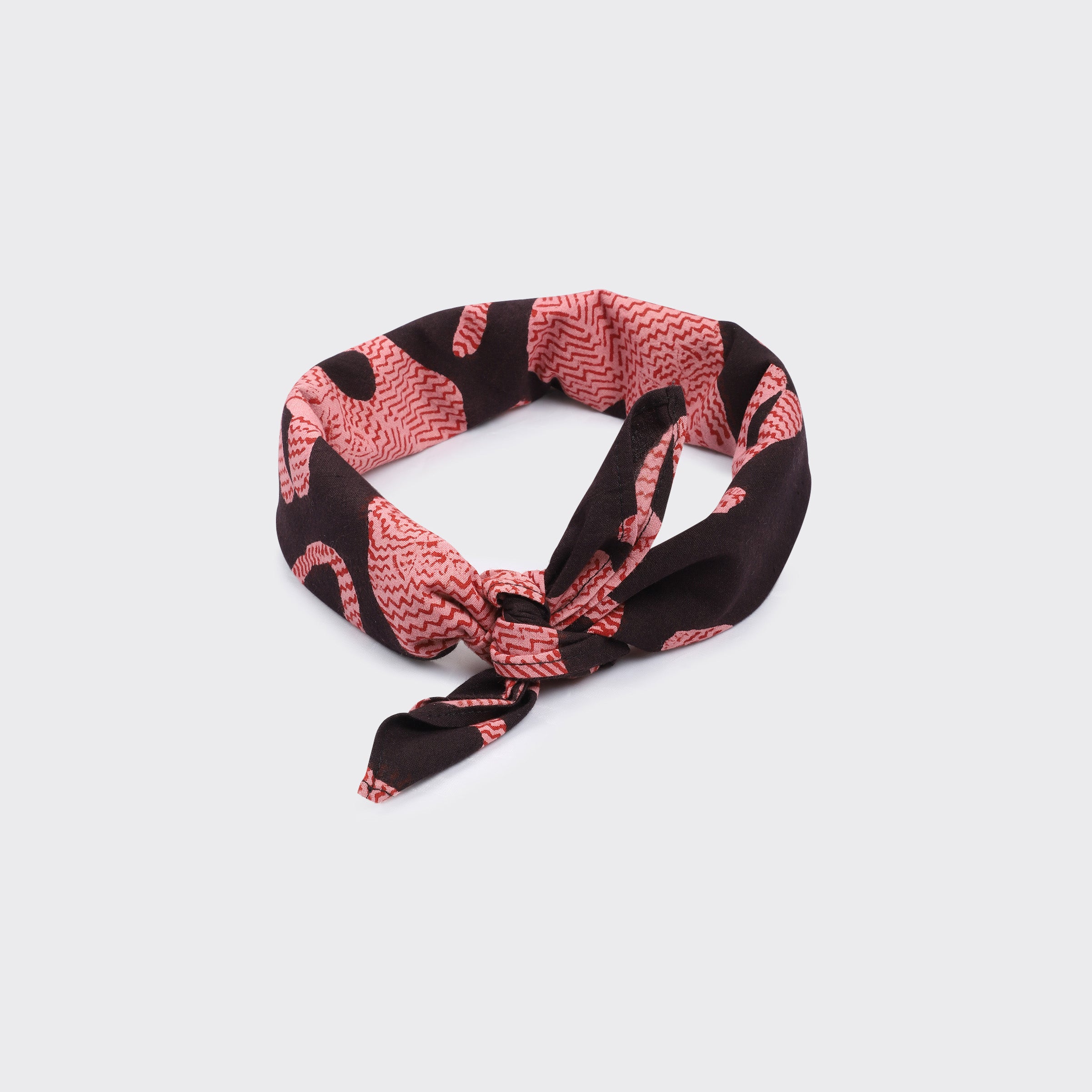 The Kardo Bandana 21" x 21" in Coral Block Print features a vibrant pattern and is shown folded and knotted against a plain light background.