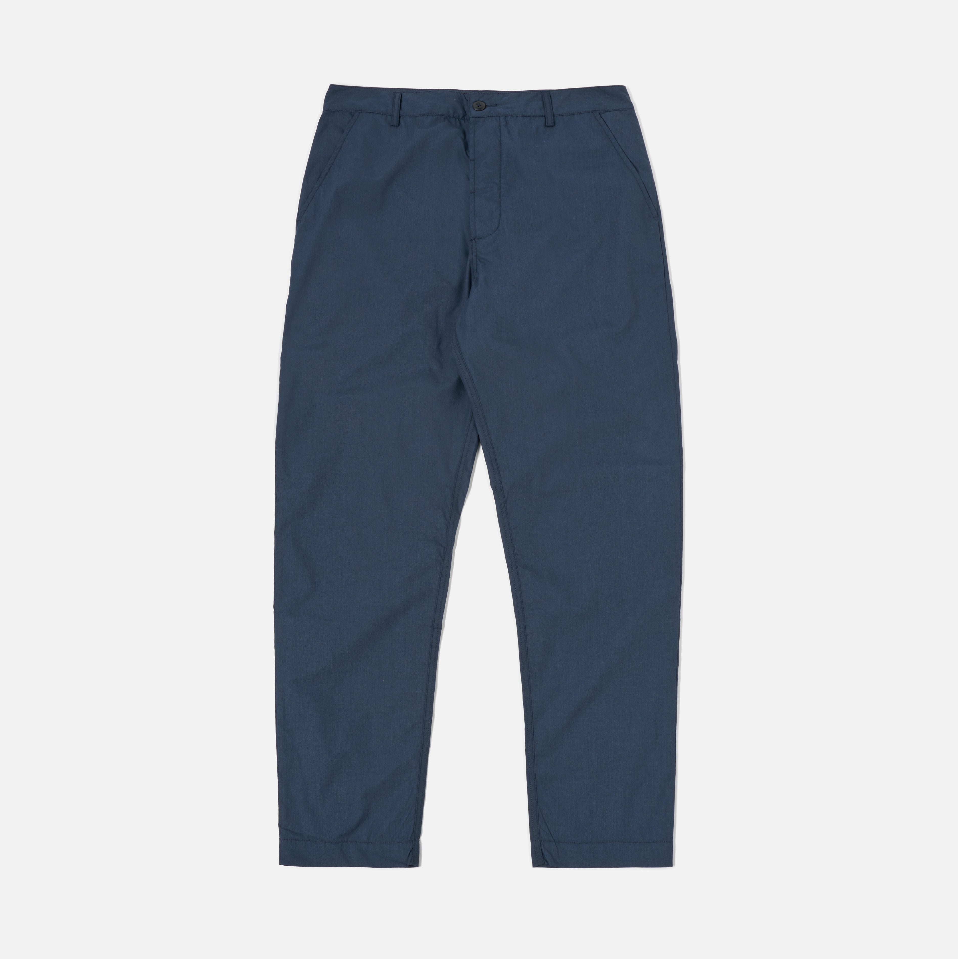A pair of Universal Works Recycled Poly Tech Military Chino trousers in navy, featuring side pockets and a button closure, laid flat on a white background.