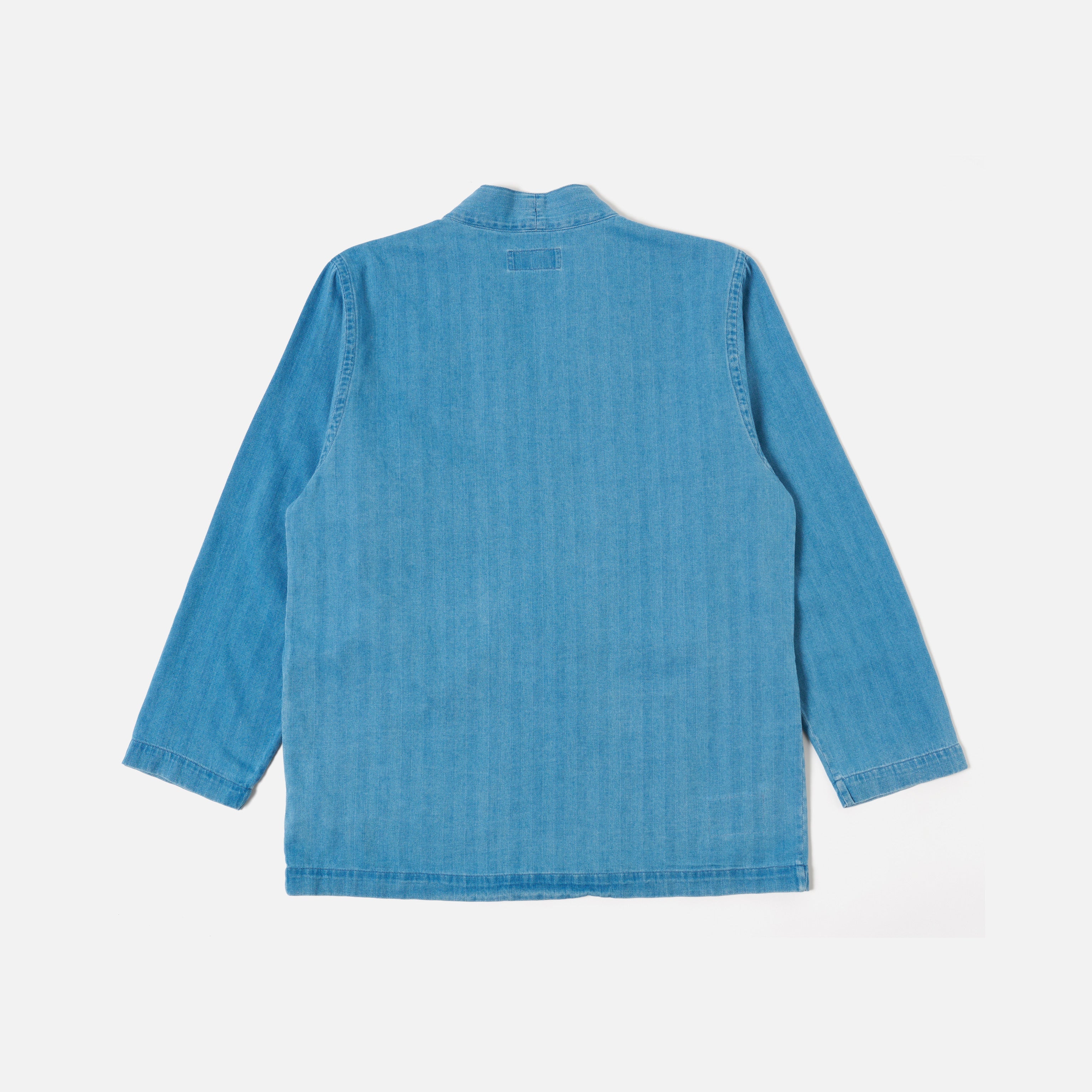 The Universal Works Herringbone Recycled Kyoto Work Jacket in Washed Indigo is displayed laid flat with the back facing up against a plain white background.