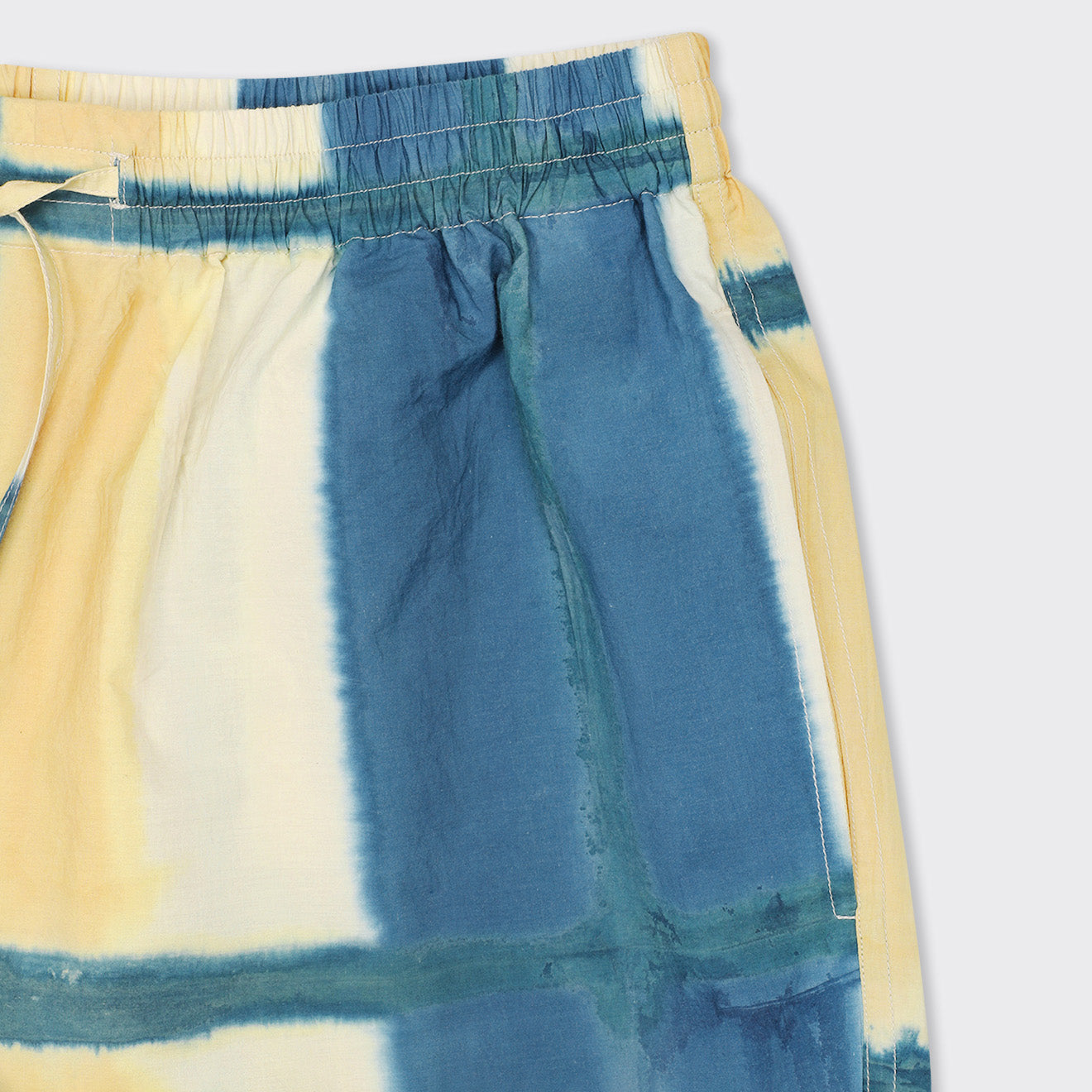 Close-up of Kardo’s Olbia Shorts in Yellow Clamp Dye, featuring an elastic waistband and drawstring, displayed on a light background.