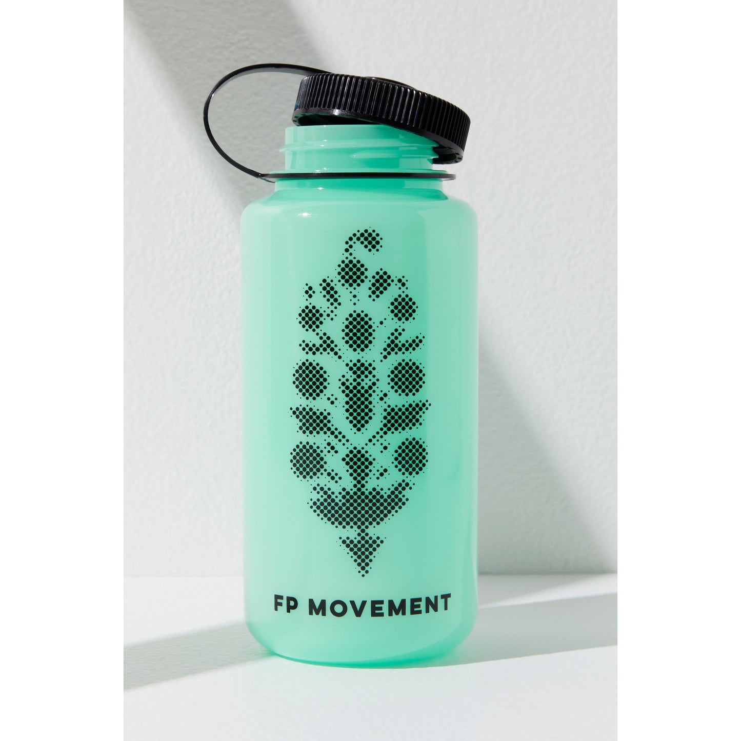A mint green GITD water bottle with a black cap and a dotted paw print design, labeled "Free People Movement," against a white background with a soft shadow.