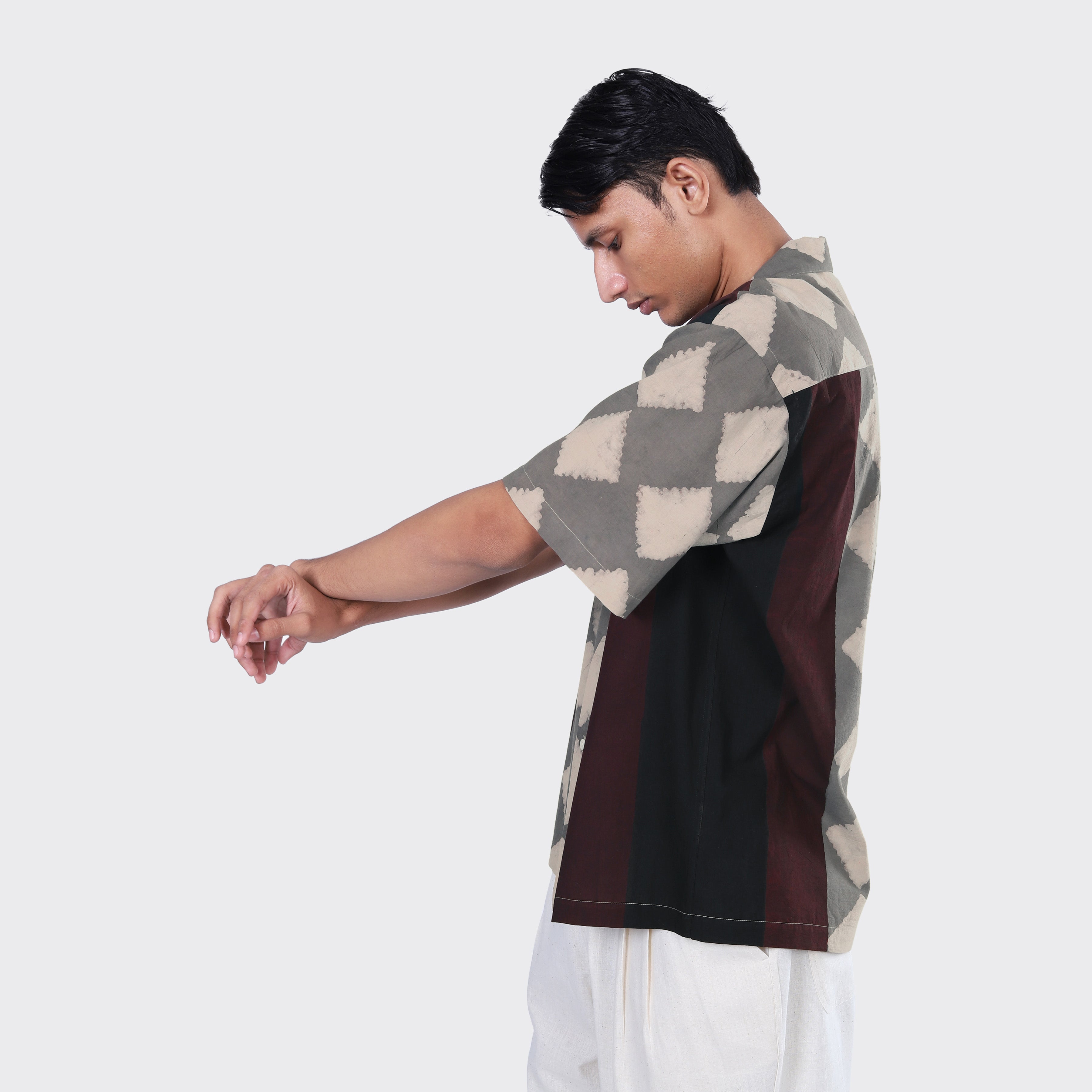 A man stands in profile against a plain background with arms extended, wearing Kardo's Rohit Shirt, Block Print 139, and white pants.