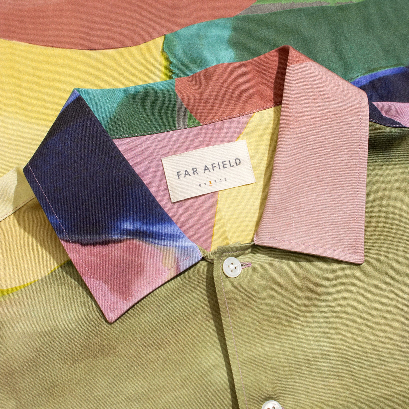 Close-up of the Far Afield Busey SS Shirt, Painted Landscape, a short-sleeve Tencel shirt with multicolored abstract patterns and an inside collar label.
