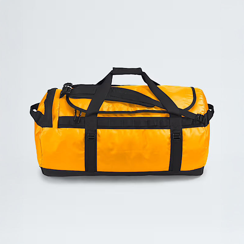 A Summit Gold Base Camp Duffel L by The North Face, featuring black straps and handles and known for its rugged durability, is set against a plain light gray background.