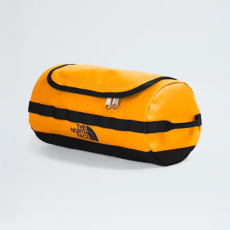 A Summit Gold Base Camp Travel Canister by The North Face, featuring a zippered top and side logo, is photographed against a light gray background. This durable bag is ideal for organizing travel or gym essentials.