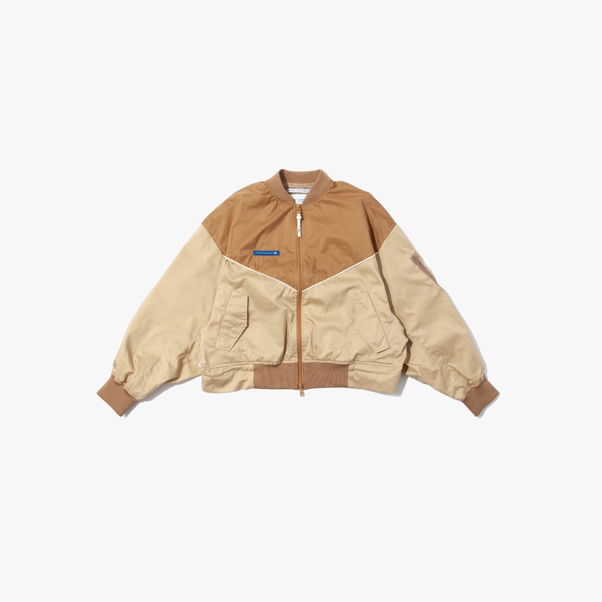 The F/CE Solotex Pigment Dye Track Blouson is a two-tone brown and beige bomber jacket with ribbed cuffs, hem, front zipper, and pockets, crafted from SOLOTEX pigment nylon fabric and shown on a plain white background.