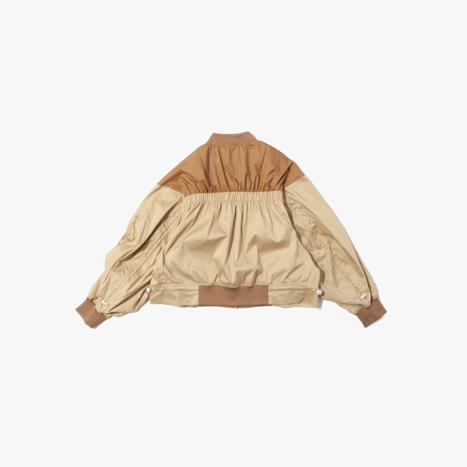 The F/CE Solotex Pigment Dye Track Blouson is a beige and brown sporty bomber jacket with ribbed elastic waistband and cuffs, crafted from SOLOTEX pigment nylon, shown flat with the back facing up on a white background.