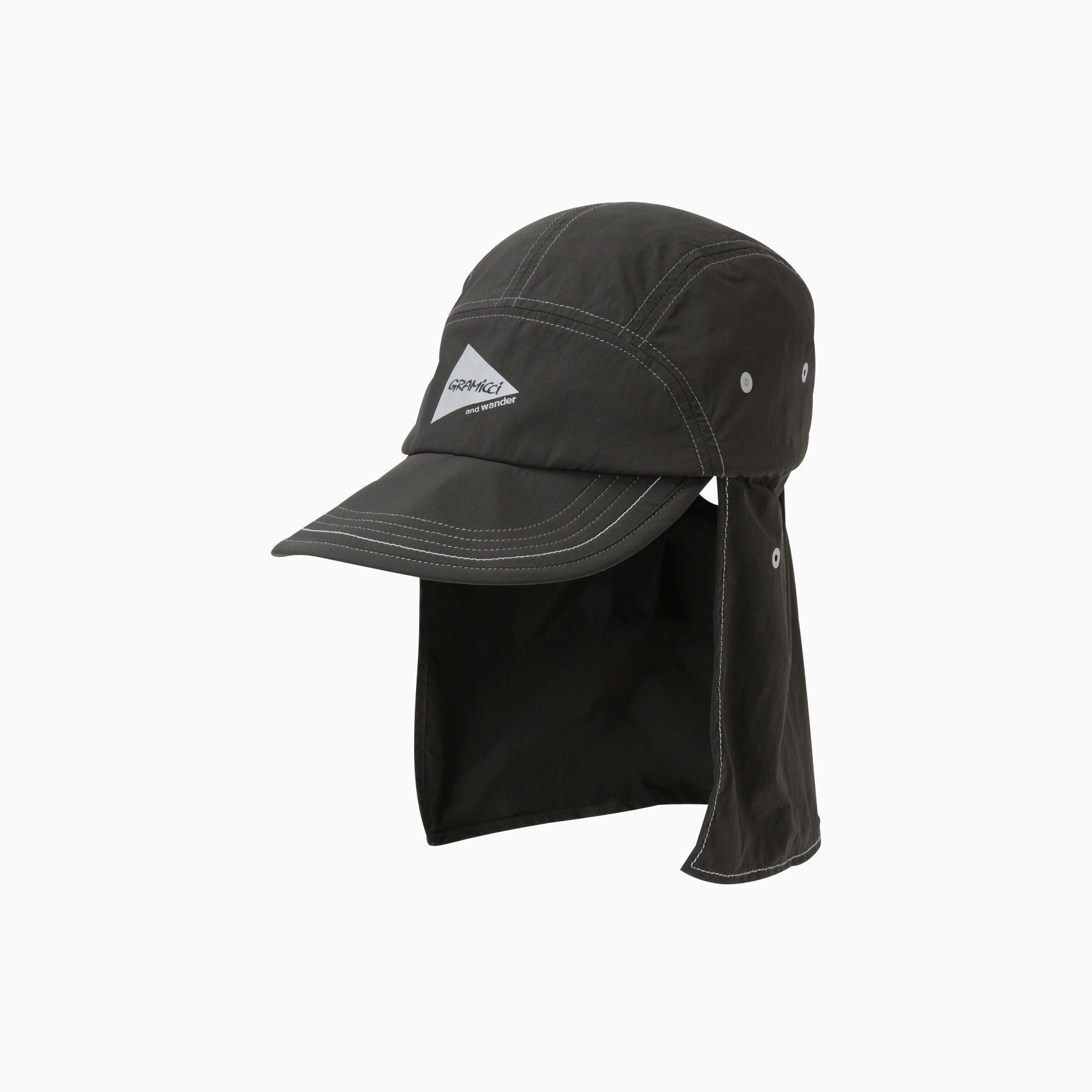 The Gramicci x And Wander Brushed Nylon Sunshade Cap features a dark gray color, long neck flap, white stitching, ventilation holes, and a small front logo.