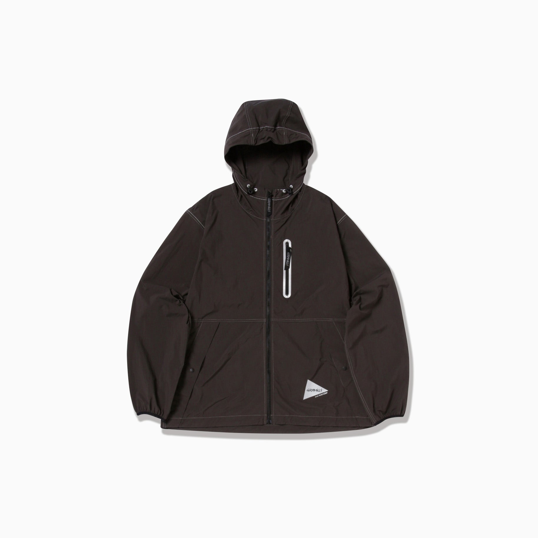 The Gramicci x And Wander Brushed Nylon Jacket is black with a hood, front zipper, two pockets, and a small logo on the lower left.