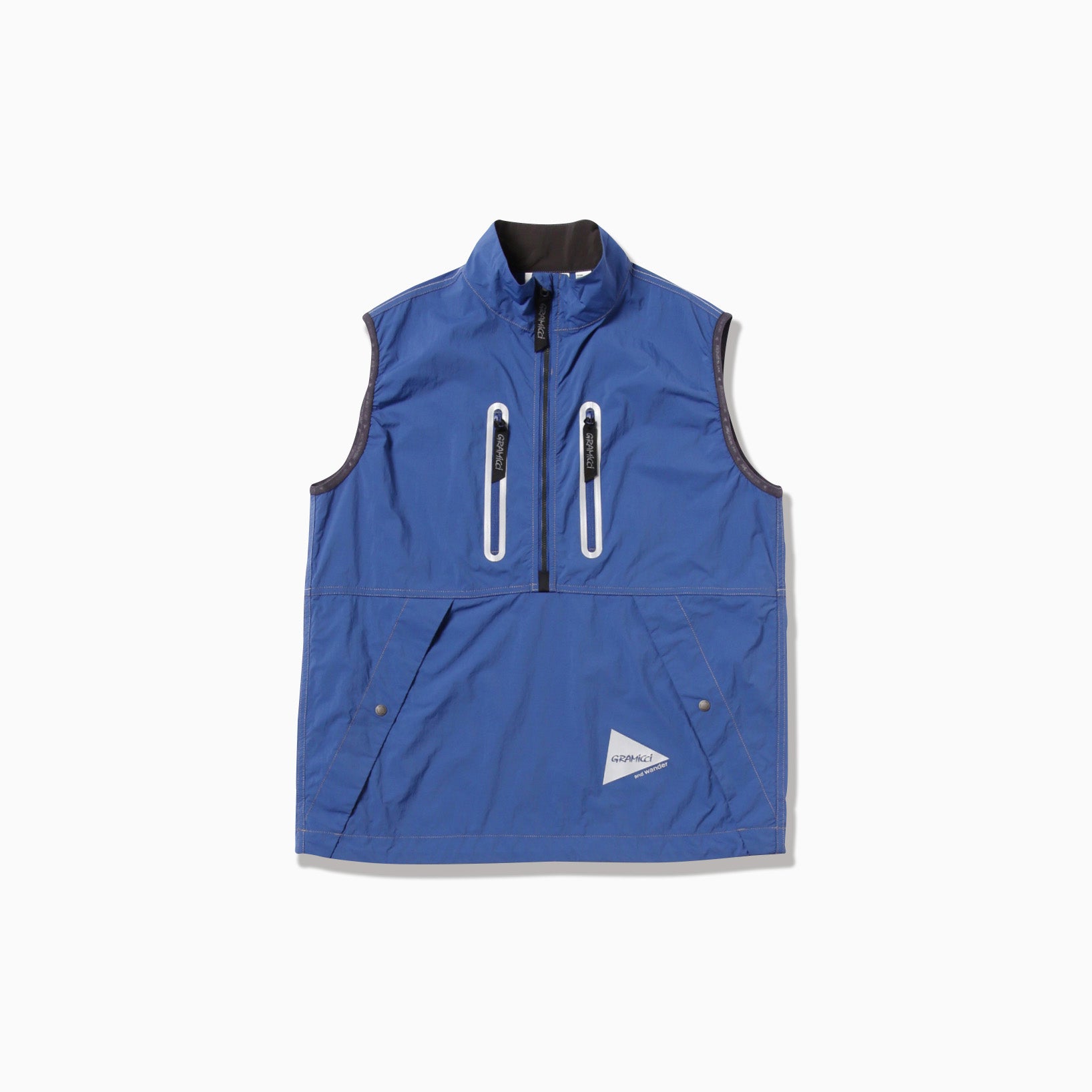 Gramicci x And Wander Brushed Nylon Vest in blue: a sleeveless design with high collar, zipper closure, and four pockets—two vertical zippered on the front and two buttoned lower down. It also sports a small triangular logo patch.