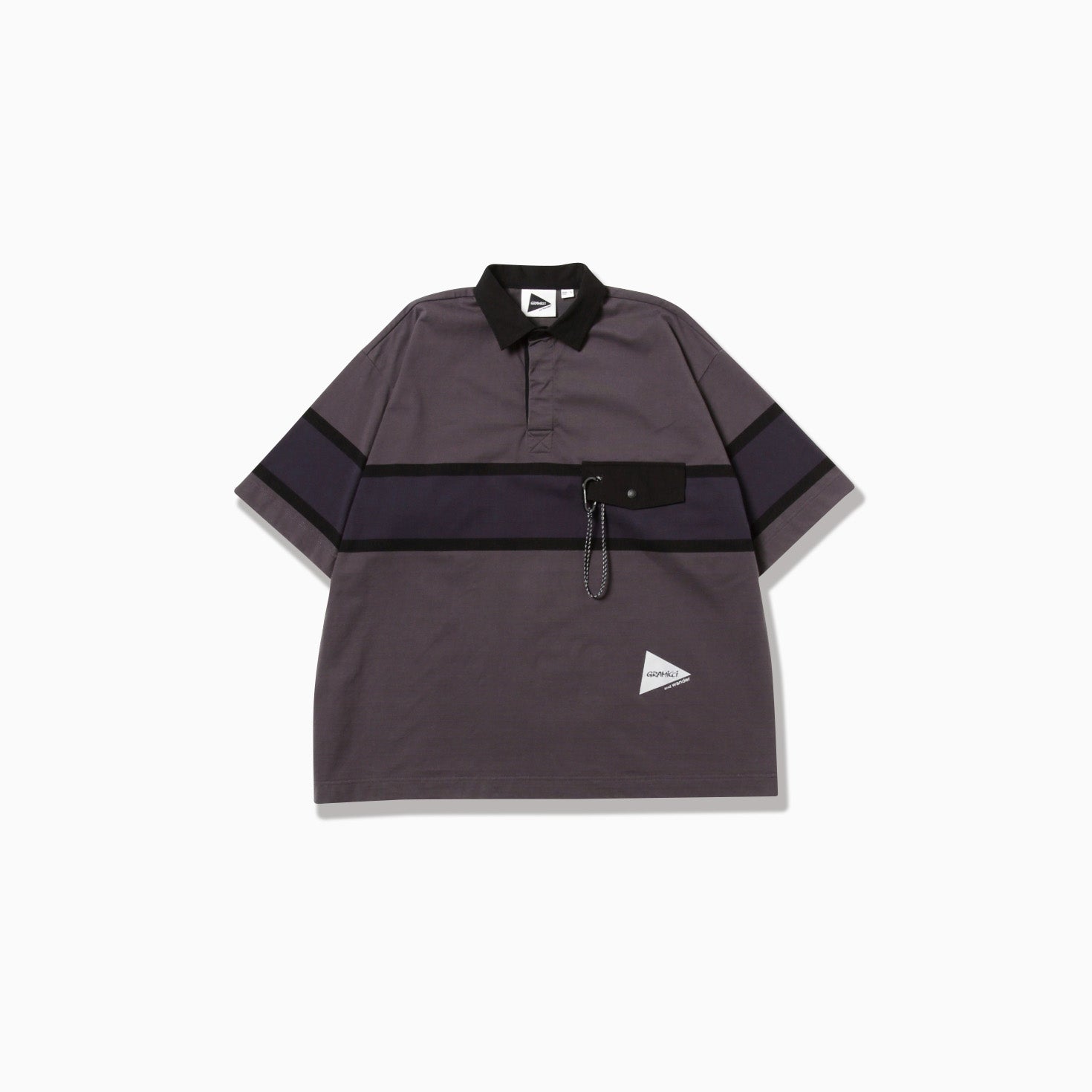 The Gramicci x And Wander Tech Rugby Shirt is a loose-fit, short-sleeve gray-and-black polo with a black collar, dark horizontal stripes, chest pocket with chain detail, and a small triangular logo near the hem.