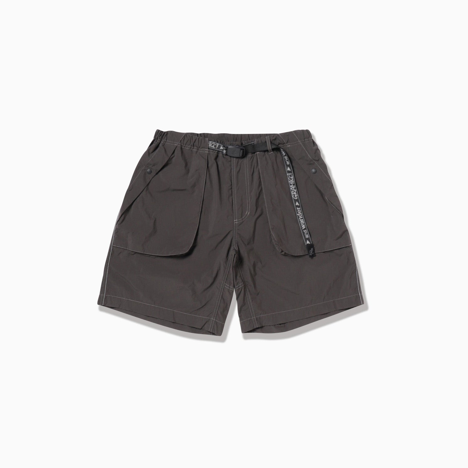 The Brushed Nylon Short by Gramicci x And Wander, in dark gray, features large front pockets, an elastic waistband, and an adjustable belt, displayed on a white background.