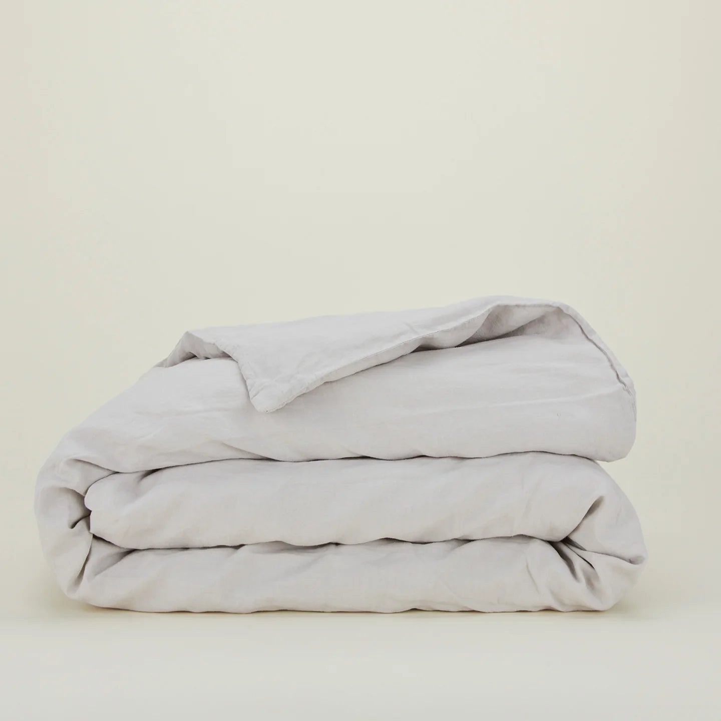 The Hawkins New York Simple Linen Bedding - Queen Duvet Cover in light gray, made from stonewashed linen, is neatly folded and displayed against a plain off-white background.