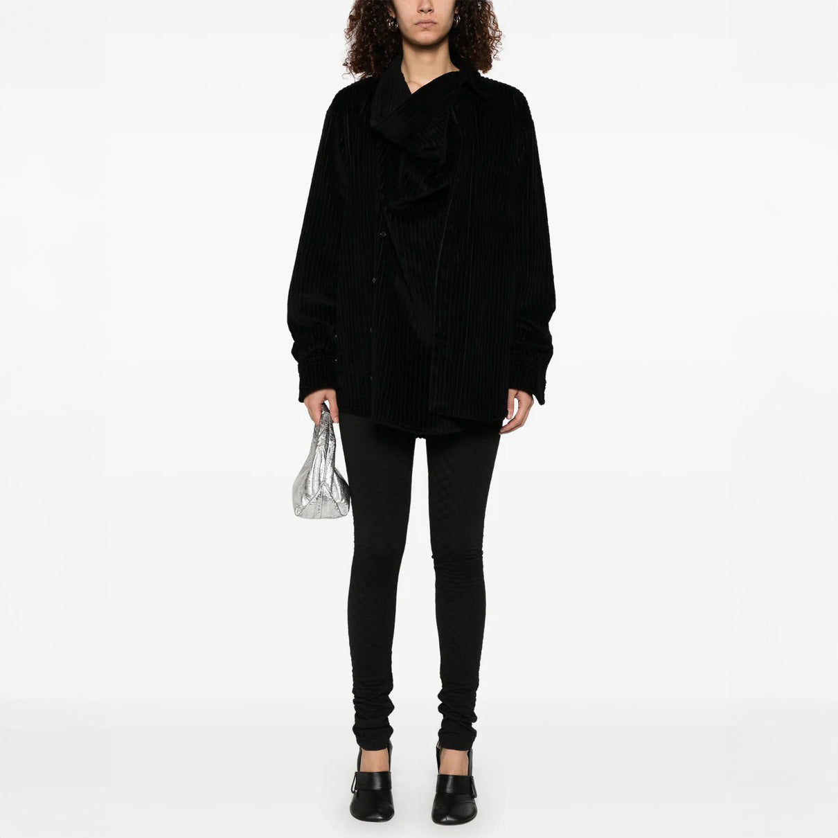 A person in a black oversized jacket and Henrik Vibskov's Honey Leggings, featuring an elastic waistband, holds a small silver handbag against a plain white background.