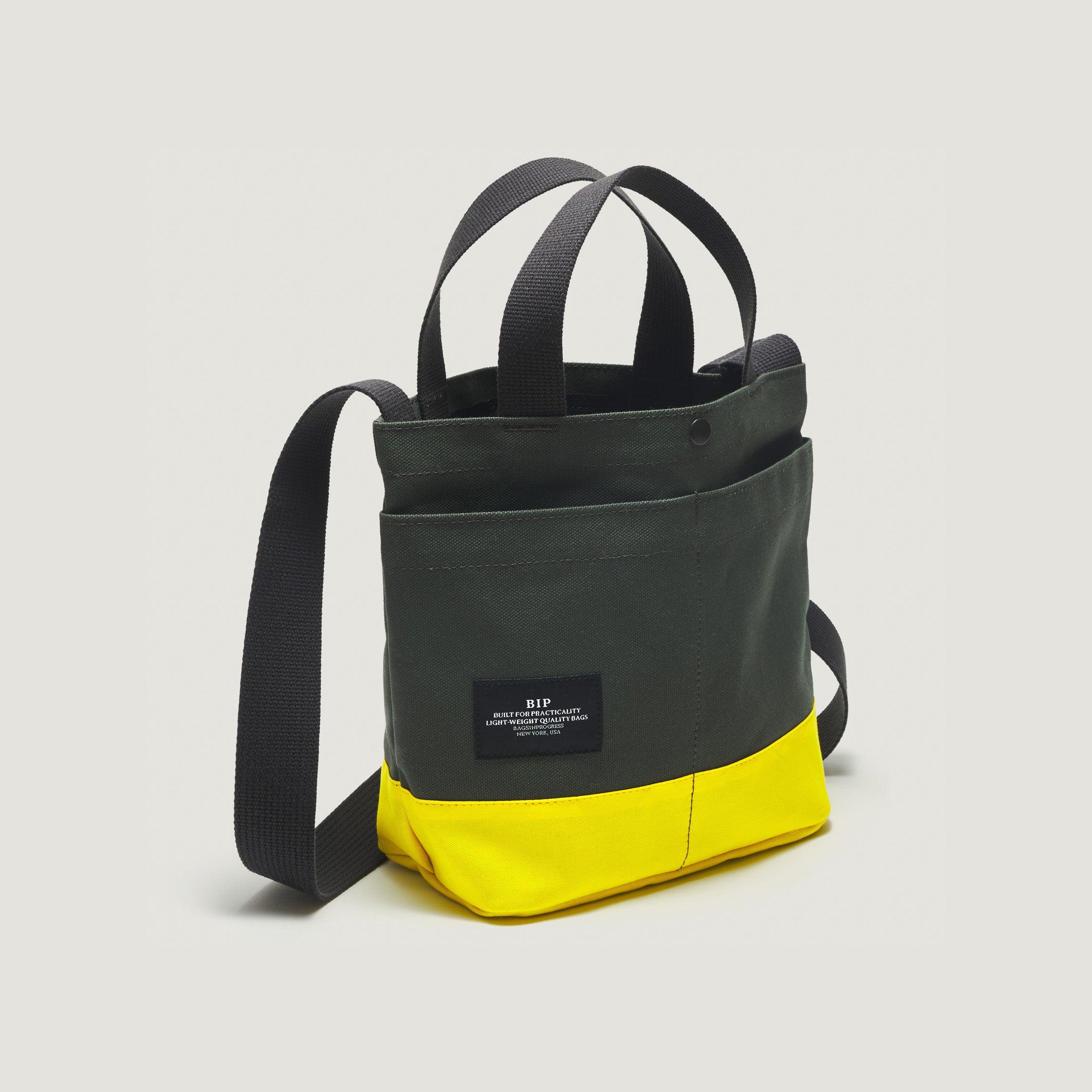The New York Tote Small, Special Edition: Forest Green/Yellow from Bags in Progress features black straps, a handy shoulder strap, and an external front pocket.