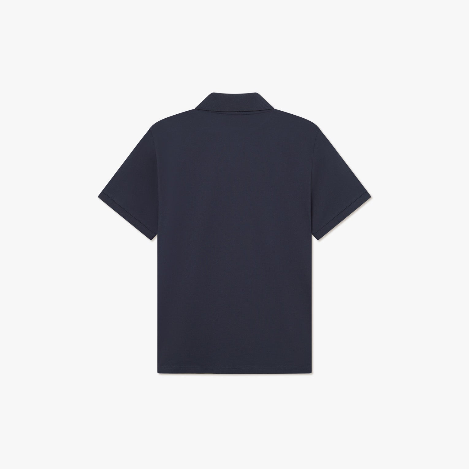 The Les Deux Pique Polo 2.0, a classic navy blue short-sleeve polo with a traditional collar, is displayed from the back against a white background, showcasing its textured piqué fabric.