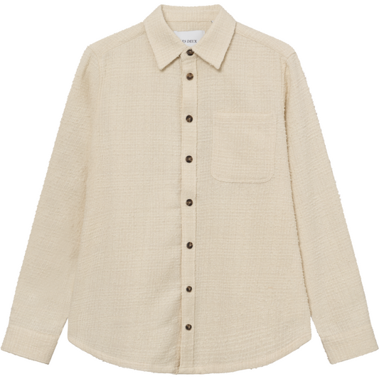 Beige corduroy shirt with a collar, button front, and a single chest pocket, crafted from recycled fibers by Les Deux, displayed on a plain background.