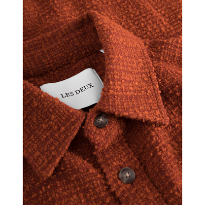 Close-up of a rust-colored "Kevin Boucle Shirt, Court Orange" with a visible label reading "Les Deux" inside the collar, and two brown buttons.