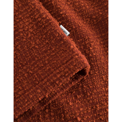 Close-up of a textured red bouclé weave fabric with a visible "Les Deux" label.
