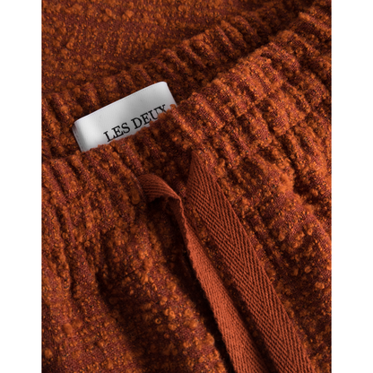 Close-up of a textured, rust-colored Kevin Boucle Shorts sweater with a white tag labeled "Les Deux".