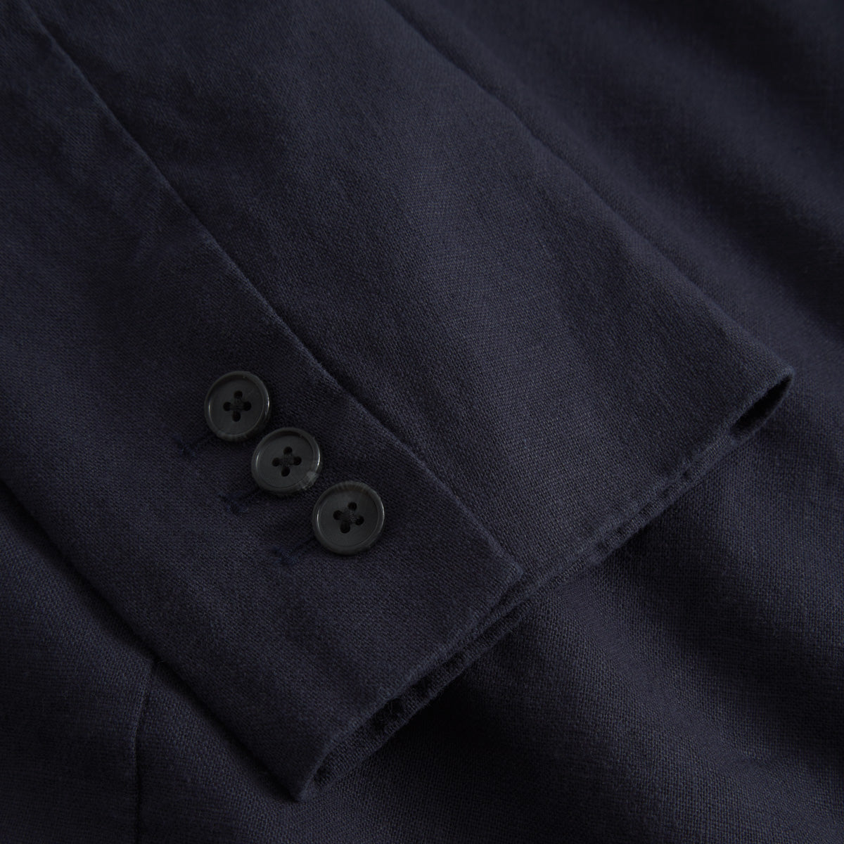 Close-up of the Les Deux James Linen Blazer's navy sleeve, featuring three black cuff buttons—a stylish and breathable option for warm weather.