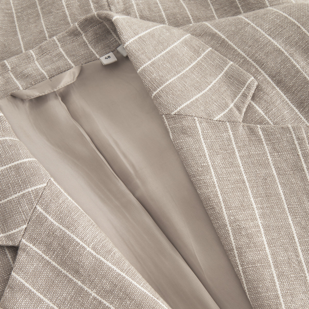 Close-up of the Les Deux James Linen Blazer in beige with white vertical stripes, showcasing its collar, lapel, inner lining, and size tag "44"—an ideal warm-weather choice.