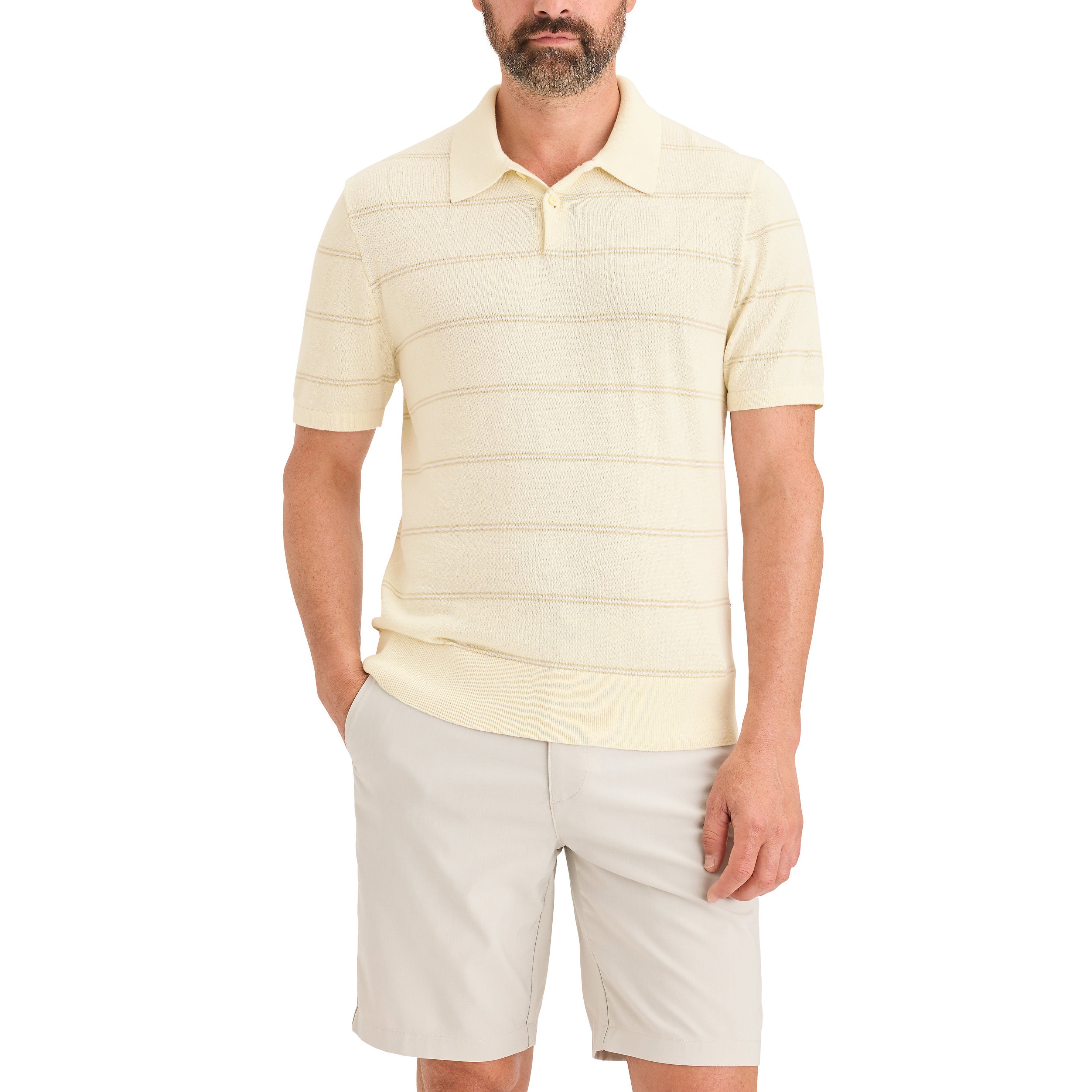 A man wears a Dockers Men's Sweater Polo in light yellow with thin horizontal stripes and light beige shorts, standing with one hand in his pocket.
