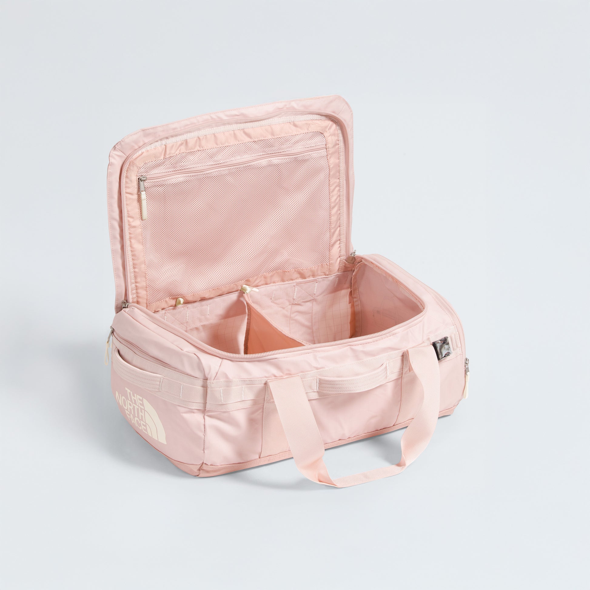 The North Face Base Camp Voyager Duffel - 42L in light pink is open, revealing its lightweight build, spacious main compartment, internal divider, and mesh zip pocket on the lid—perfect for travel.