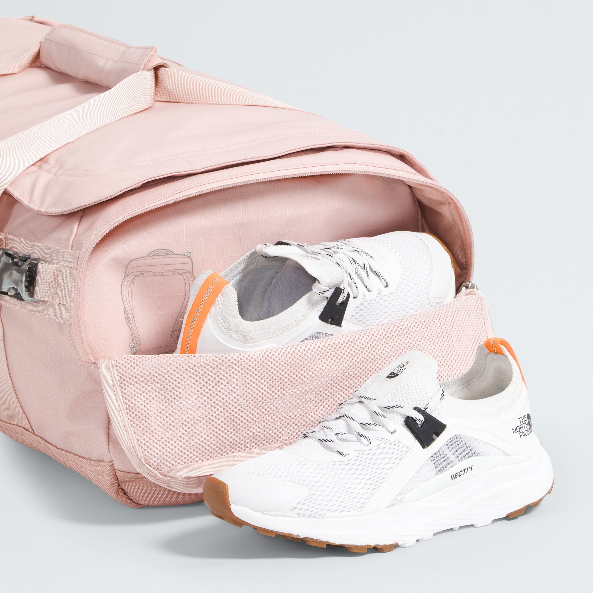 The North Face Base Camp Voyager Duffel - 42L in pink, with its lightweight build and side compartment, is partially open to display white sneakers with orange accents—ideal for stylish, organized travel.