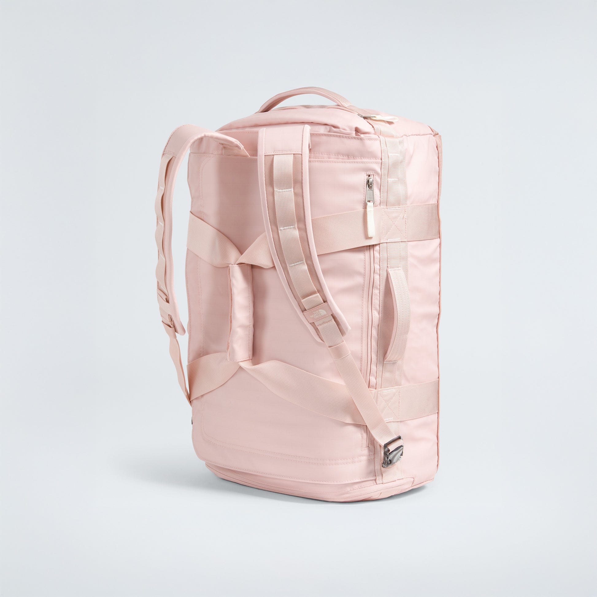 The North Face Base Camp Voyager Duffel - 42L is a light pink bag with backpack straps, top and side handles, and zippered compartments—an ideal lightweight travel companion that stands upright on a plain light background.