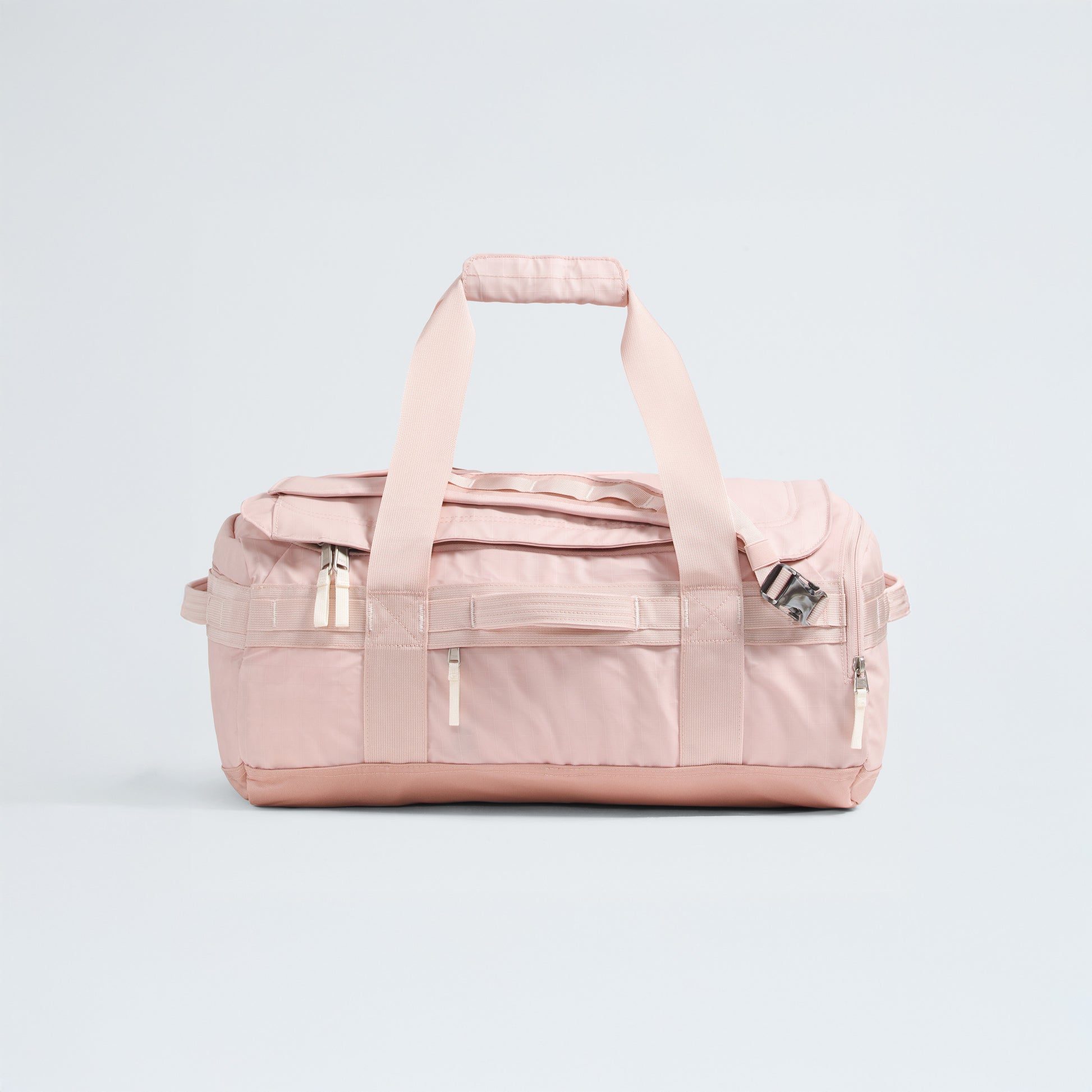The North Face Base Camp Voyager Duffel - 42L is a light pink bag with two handles, a shoulder strap, and multiple zippered compartments—its lightweight design makes it the ideal travel companion, shown against a plain light background.
