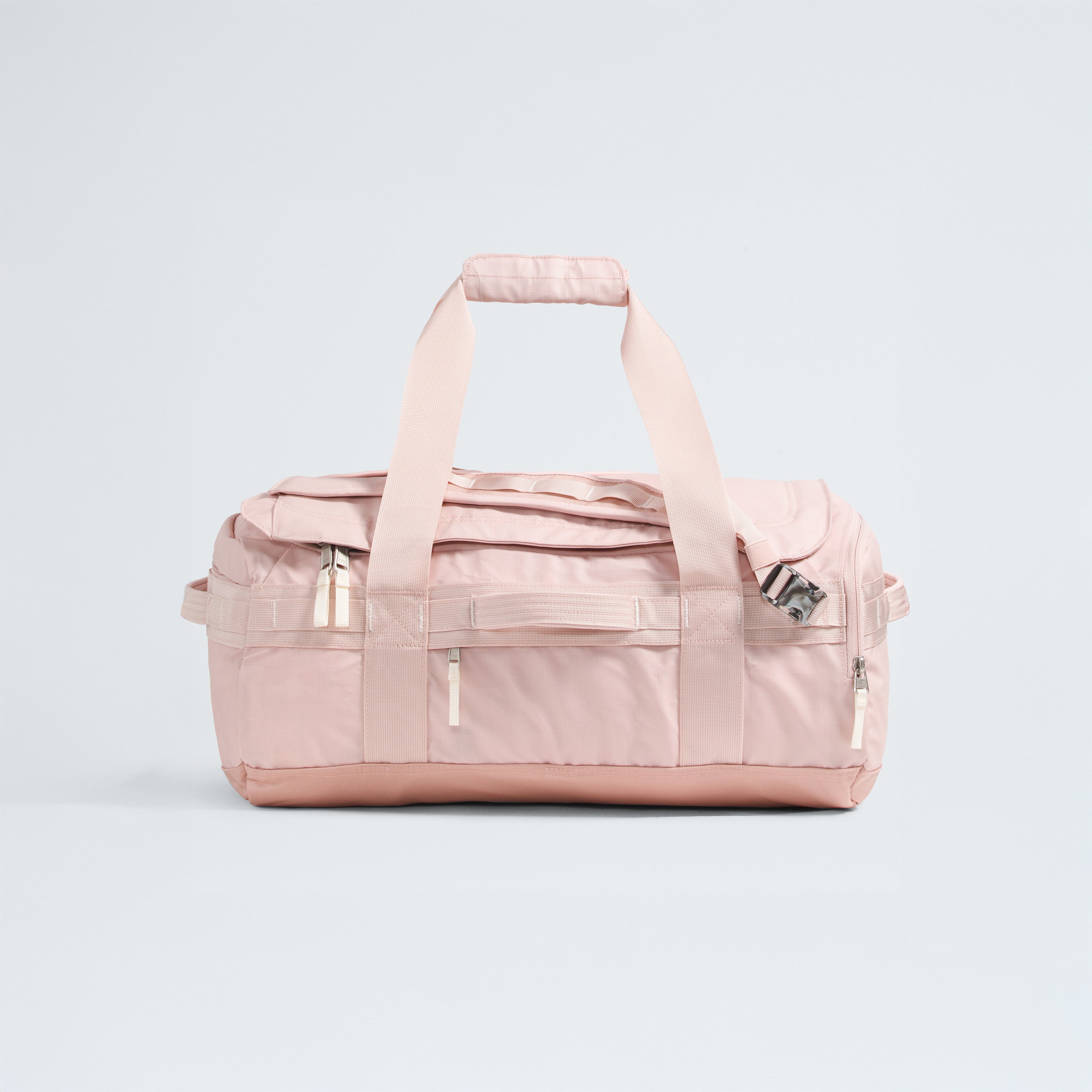 The North Face Base Camp Voyager Duffel - 42L is a light pink bag with two handles, a shoulder strap, and multiple zippered compartments—its lightweight design makes it the ideal travel companion, shown against a plain light background.