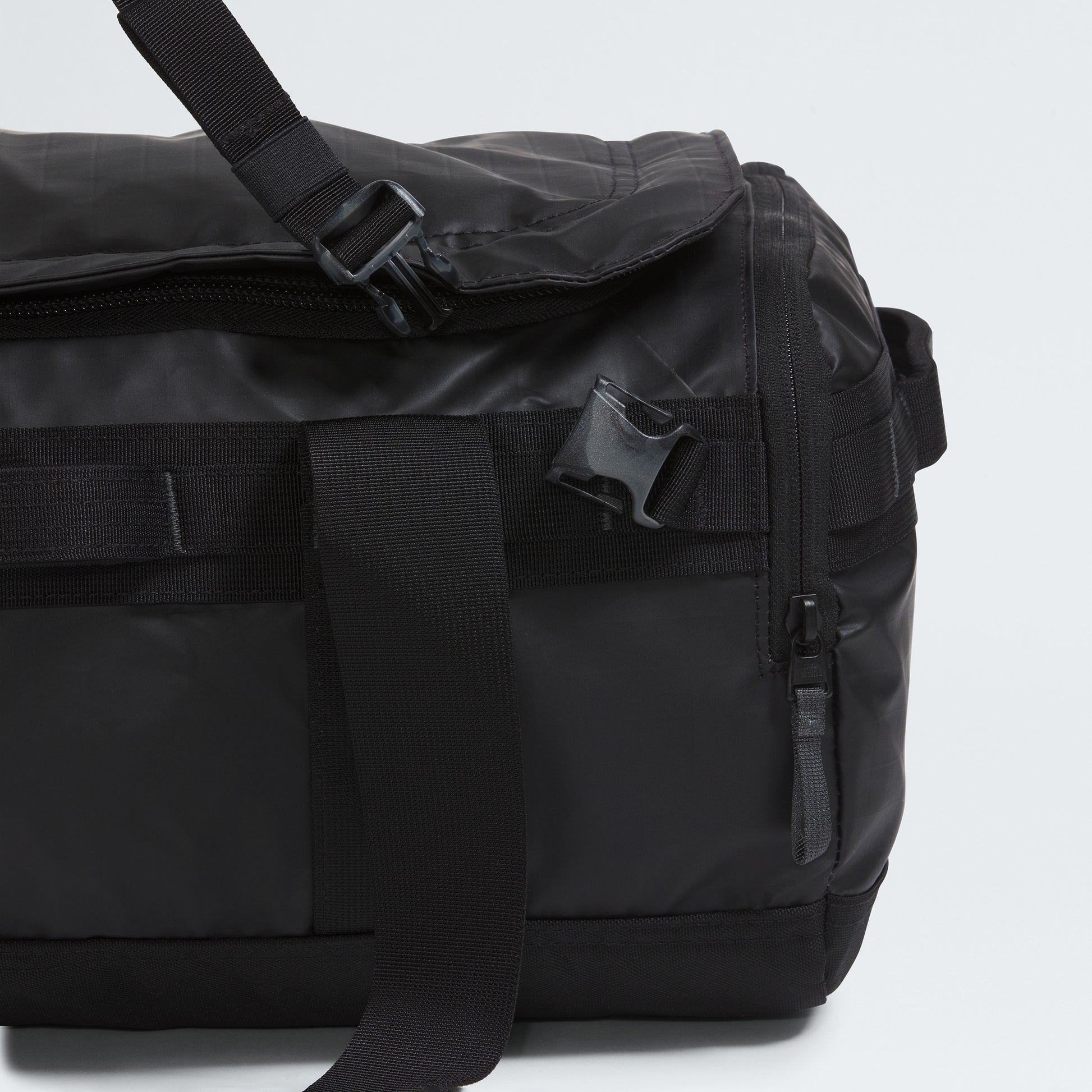 Close-up of The North Face Base Camp Voyager Duffel - 42L, featuring a zipper, buckle, and adjustable strap. Its lightweight build makes it an ideal travel companion against a plain background.