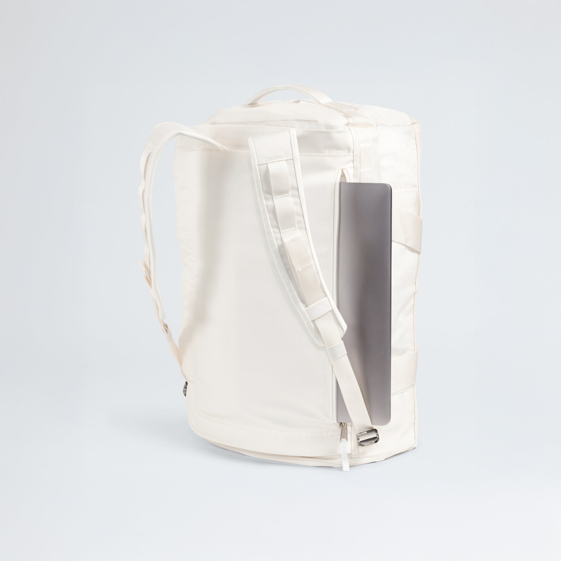 The North Face Base Camp Voyager Duffel - 42L features a top handle, padded shoulder straps, and a side zipper pocket holding a closed laptop. Its lightweight build makes it perfect for travel, shown here against a plain light background.