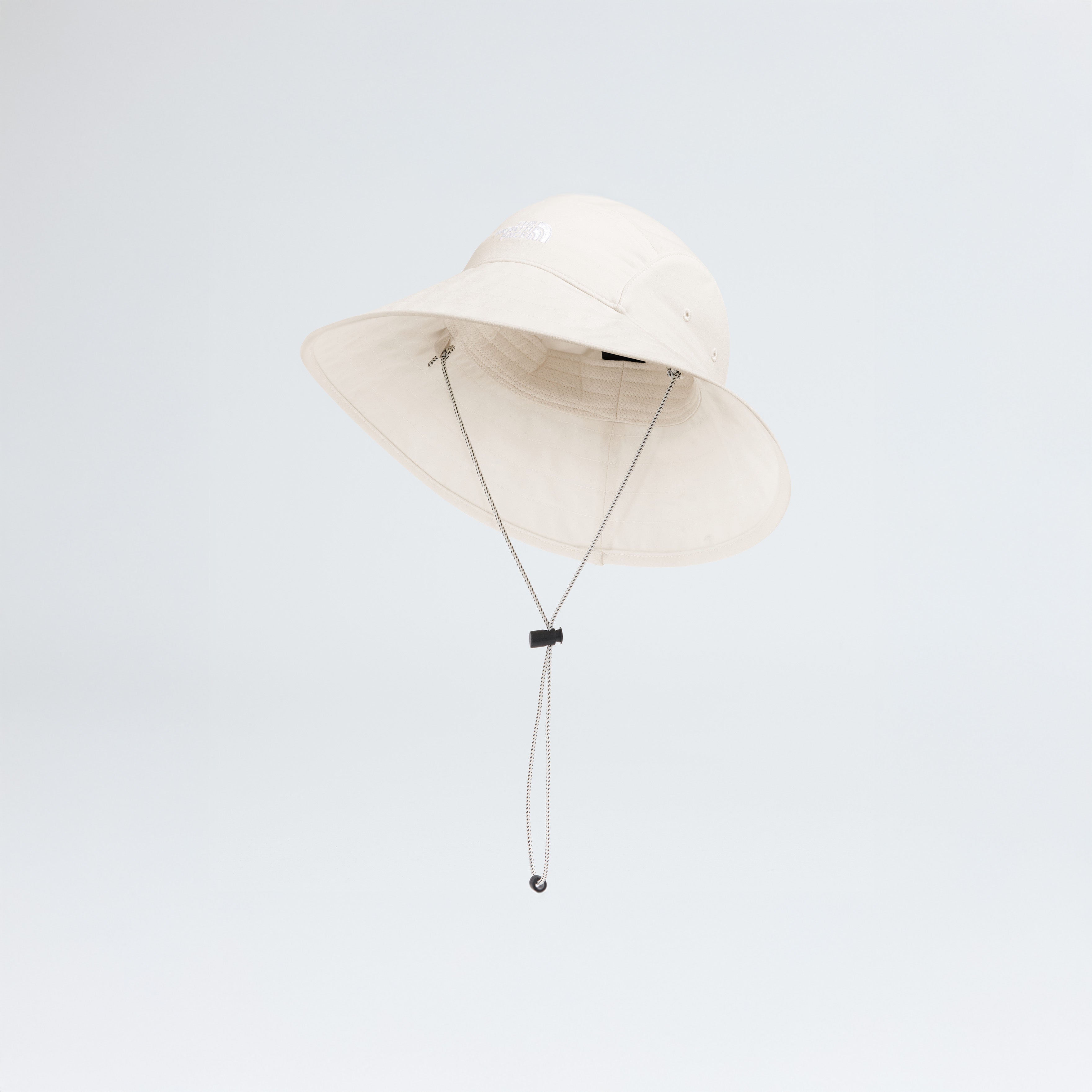 The North Face's W Class V Brimmer, a beige wide-brimmed hat with a chin strap, offers sun and UV protection against a plain background.