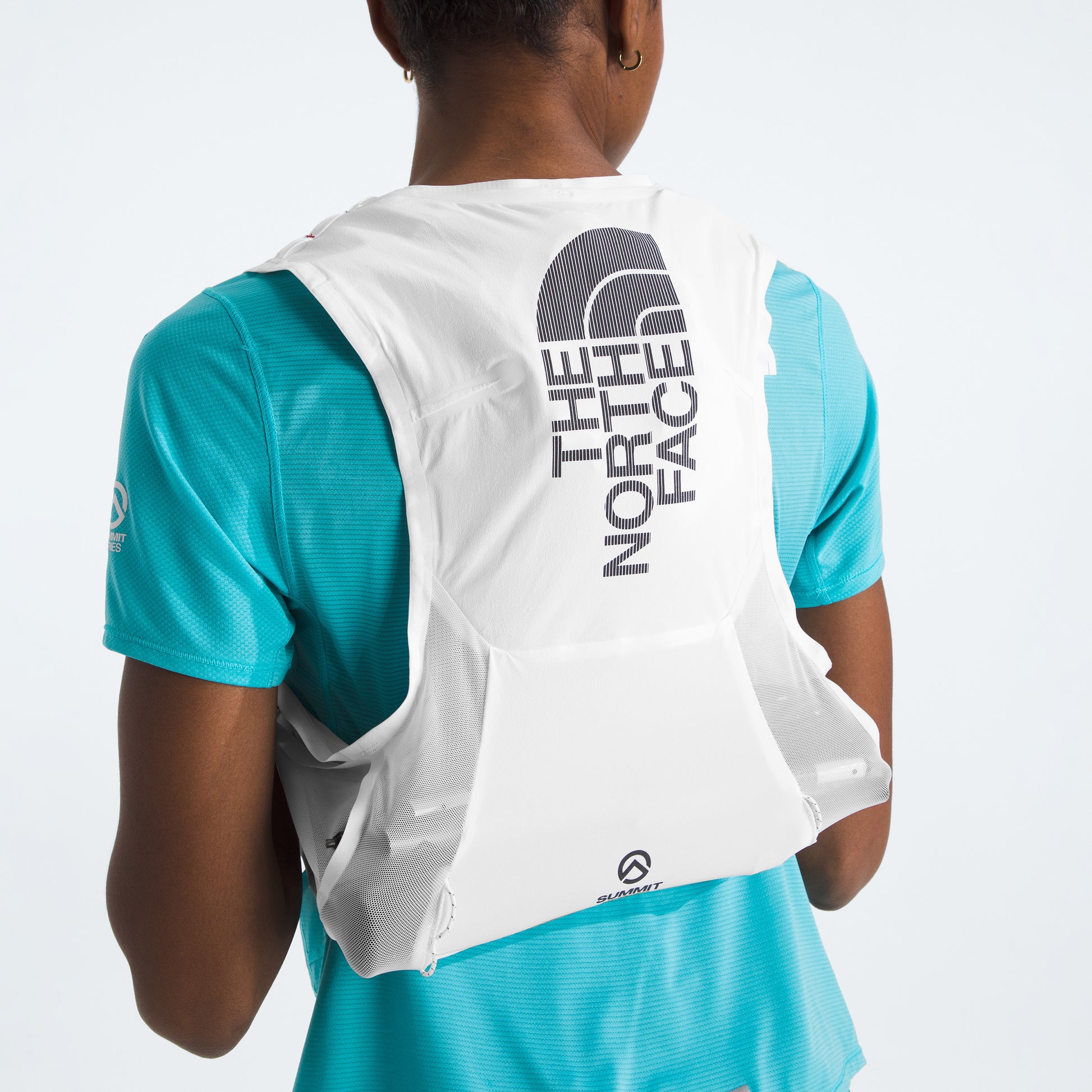 A person is seen from the back, ready for race day, wearing a U Summit Run Vest 5 by The North Face over a blue shirt.