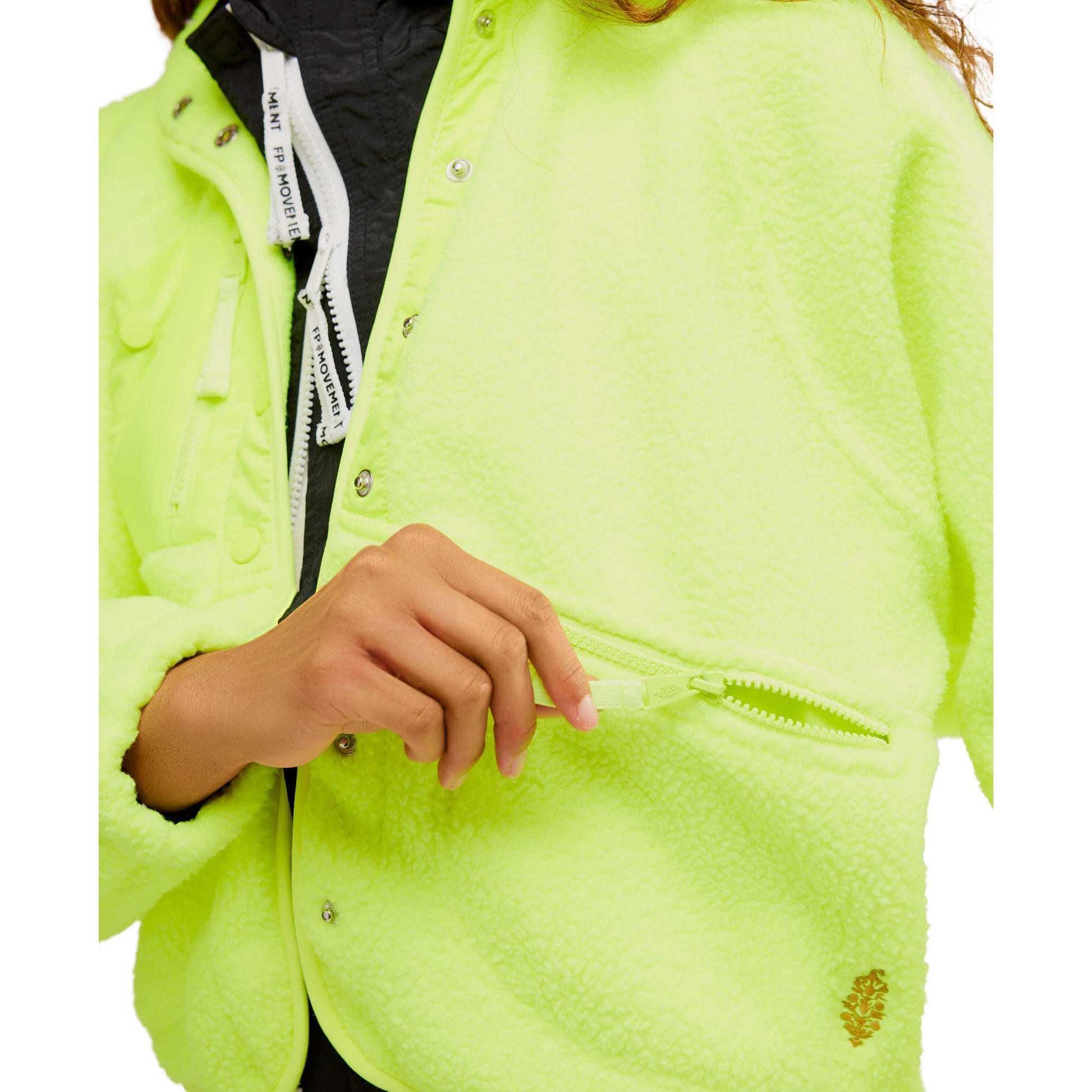 Close-up of a person wearing a Free People Movement Hit The Slopes Jacket in Highlighter, unzipping the zippered pockets with detailed embroidery near the zip.