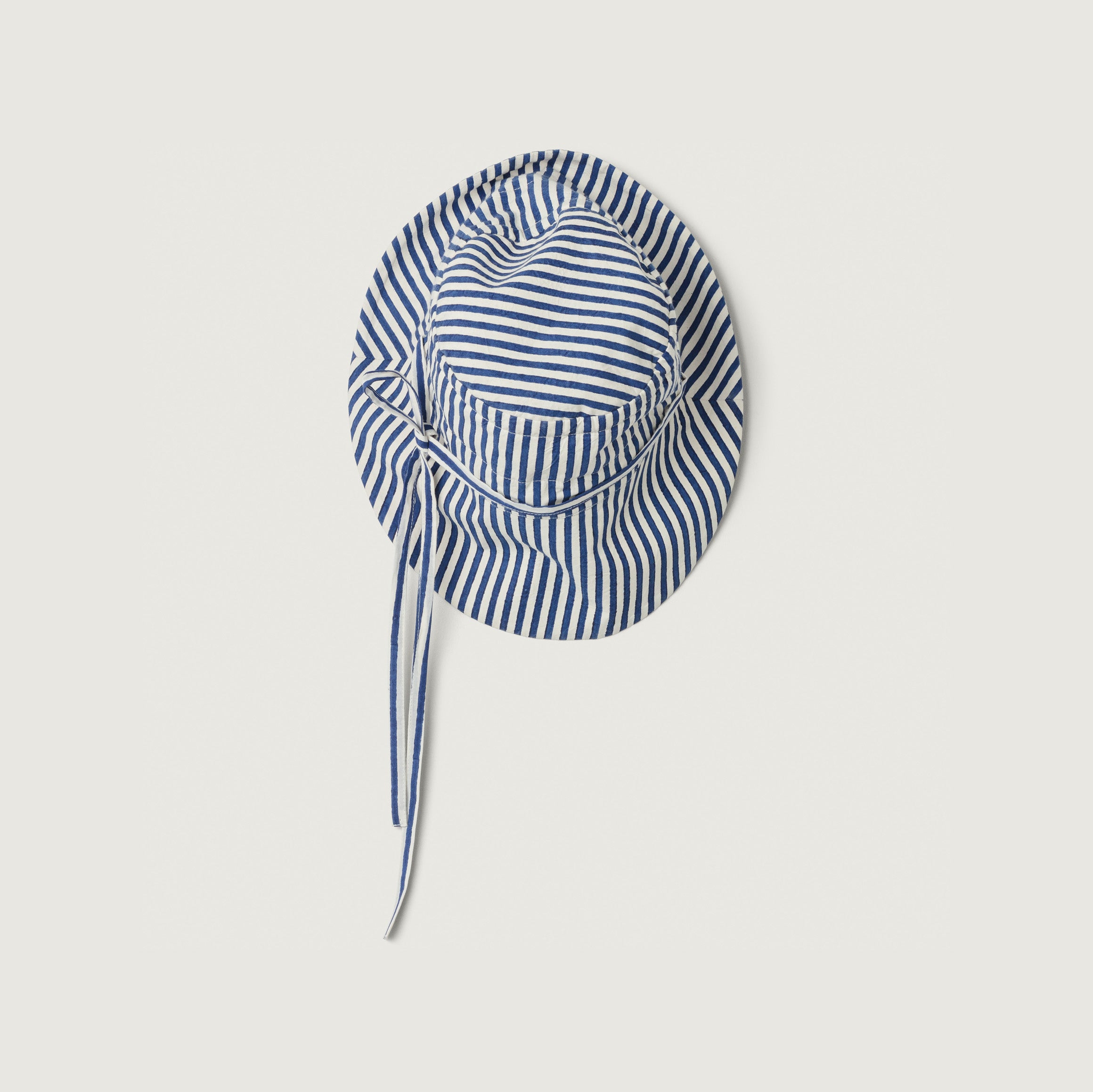 The Sylvie, Blue Stripe hat by Jan Machenhauer features blue and white stripes, a brim, and chin ties, shown on a plain white background.