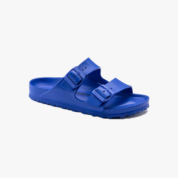 The Birkenstock Arizona EVA Regular sandal in Ultra Blue features two adjustable buckle straps, a contoured waterproof EVA footbed, and a textured sole. Shown on a white background. Unisex sizing offers a comfortable fit for everyone.