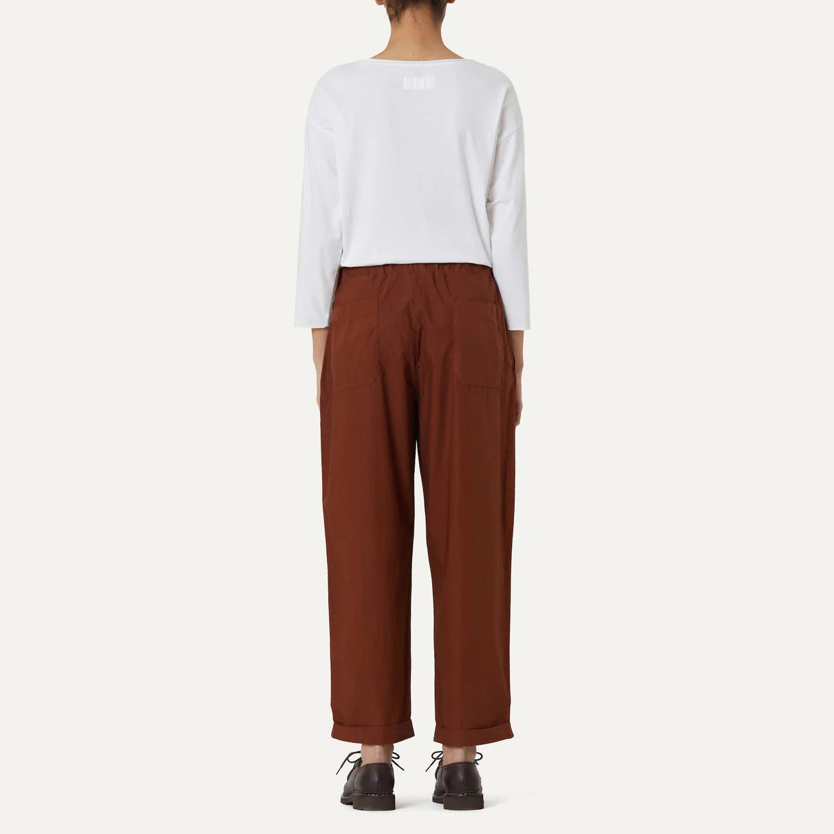 A person in a white long-sleeve shirt and Labo Art's brown cotton Panta Vela Pant with an elastic waistband is shown from the back against a plain background.