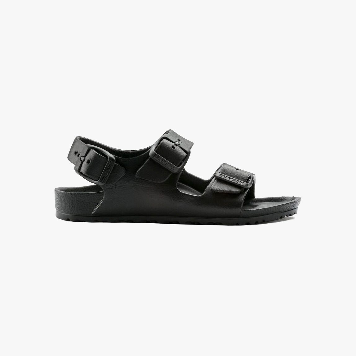 The Birkenstock Milano EVA Kids in black is an ultra-lightweight sandal with a textured sole and three adjustable buckle straps, shown in a side view on a white background.