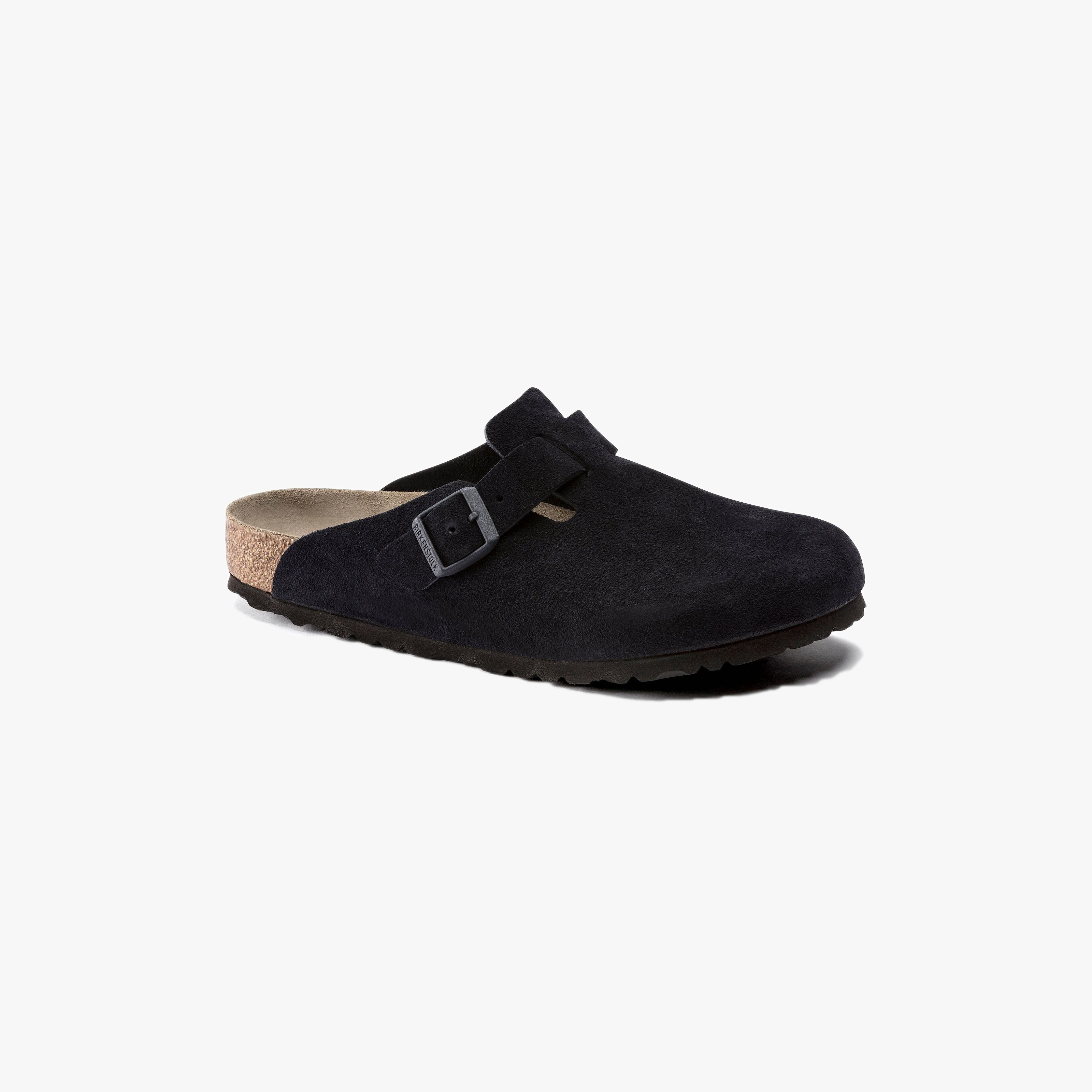 The Birkenstock Boston Suede, Midnight features a black suede upper, soft footbed, adjustable buckle strap, cork sole, and a slightly raised heel, pictured on a plain white background.