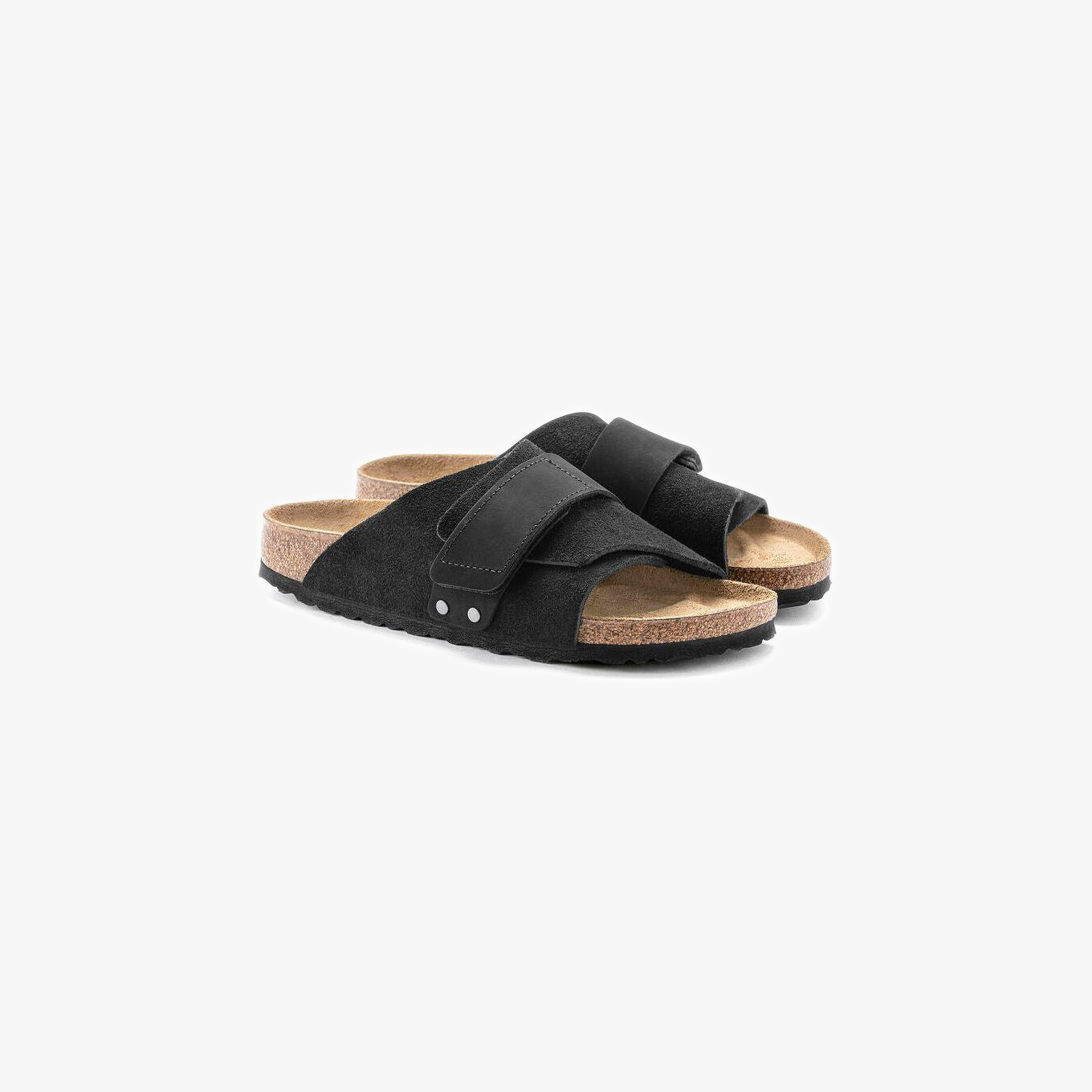 A pair of Birkenstock Kyoto Suede sandals in black, featuring adjustable hook-and-loop straps, cork-latex footbeds, and textured soles, shown on a white background.