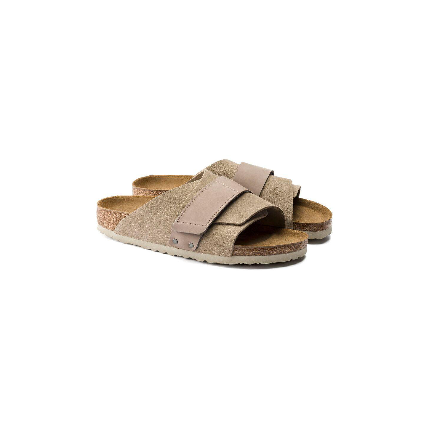Birkenstock Kyoto Suede in Taupe: beige slip-on sandals with suede upper, wide straps, cork-latex footbed, and textured rubber soles, shown on a white background.